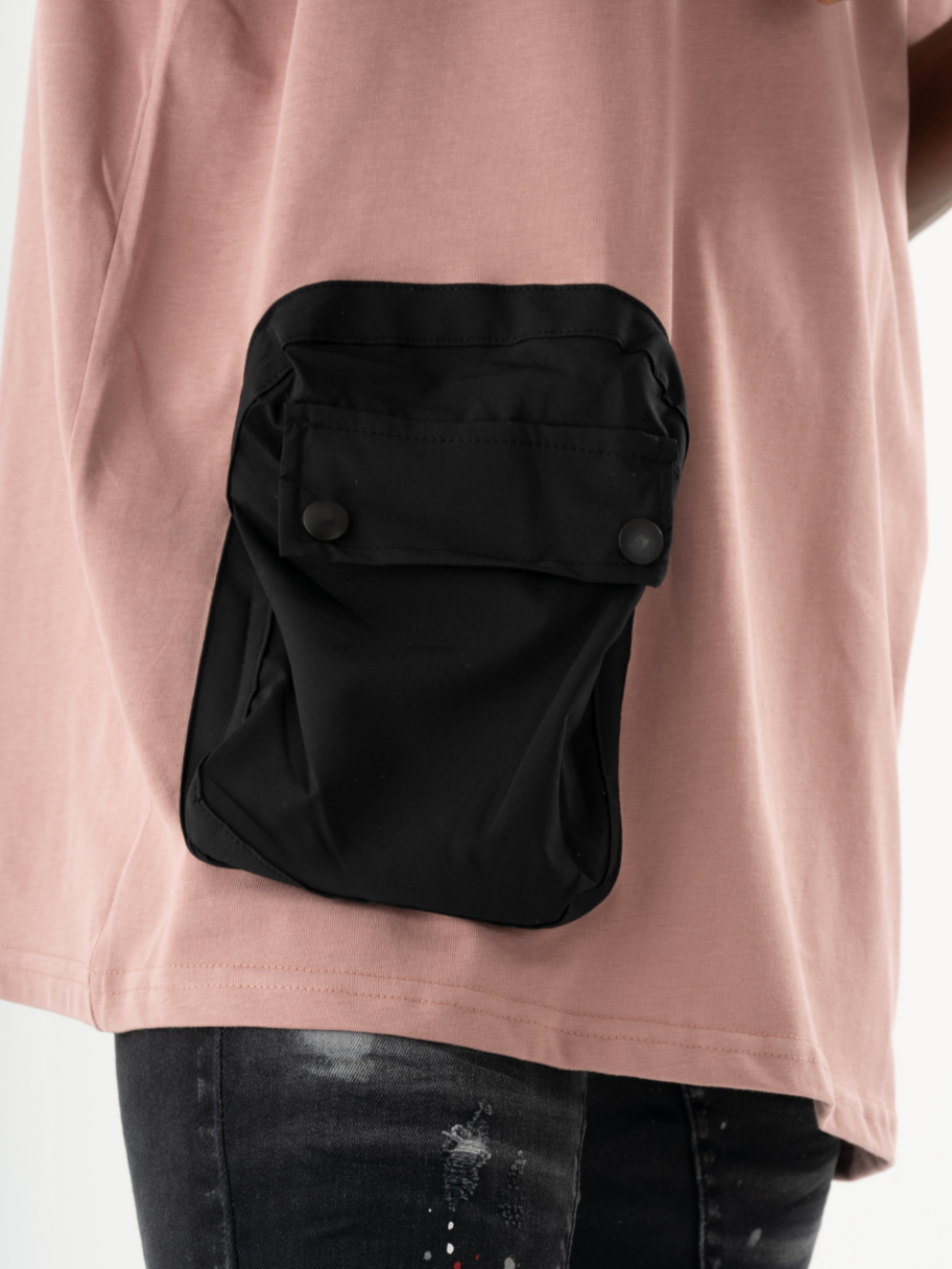 Close-up of a person wearing a DUNE T-SHIRT with a black buttoned front pocket, paired with distressed black jeans.