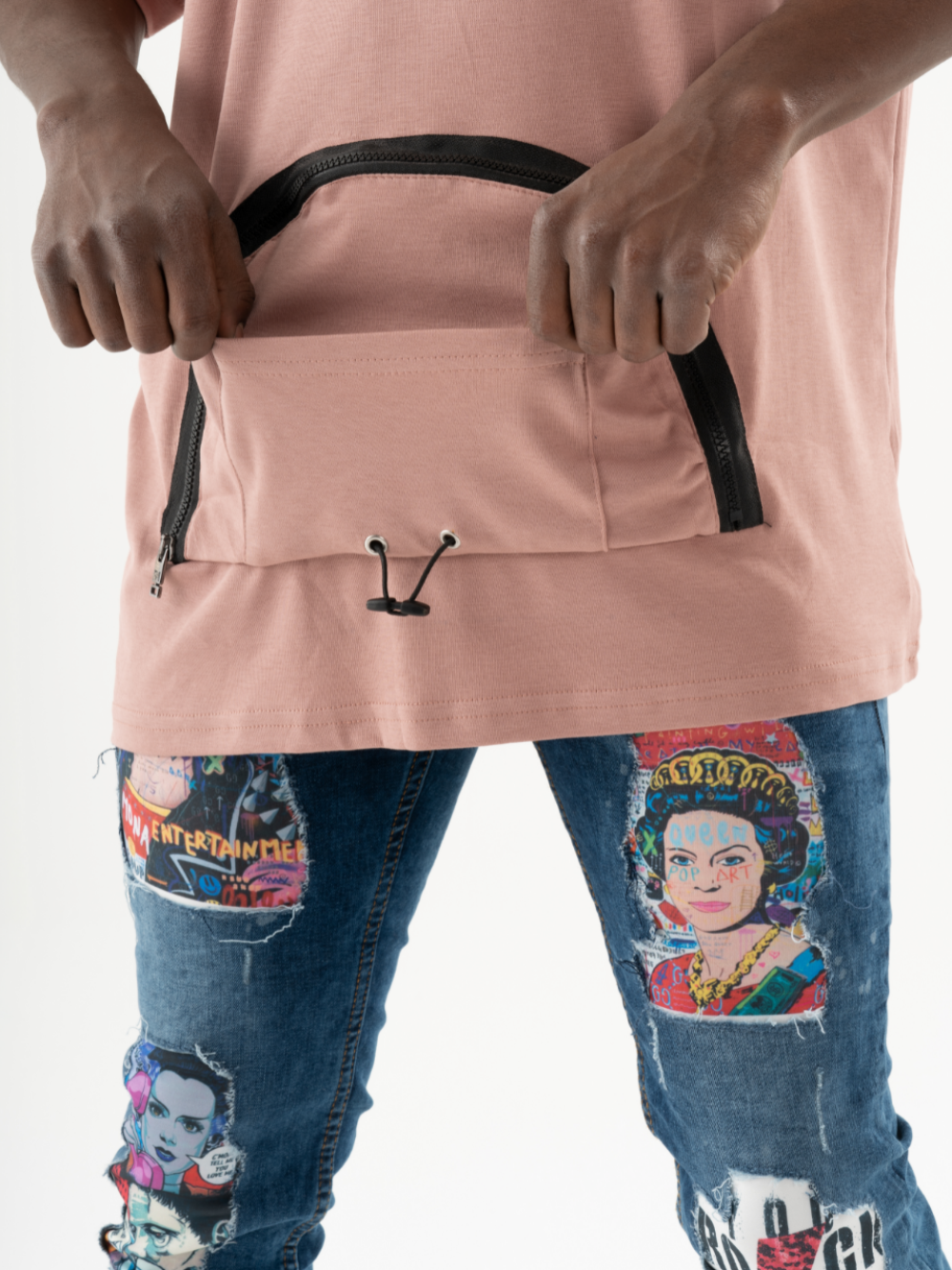 A person wearing a salmon-colored T-shirt and jeans with colorful patches holds a KANGAROO T-SHIRT against their torso.