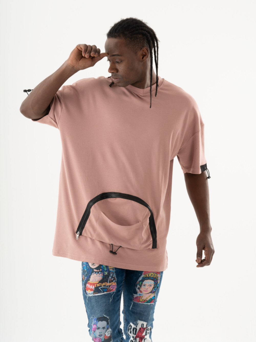 A person wearing a salmon-colored KANGAROO T-SHIRT with a zippered pouch and colorful jeans stands adjusting their hat, looking to the side.