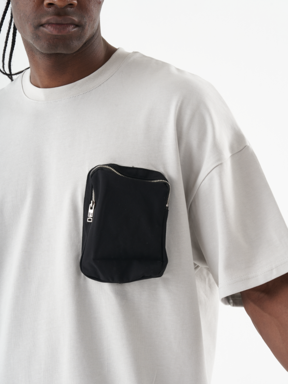 Person sporting a casual look with a KLOUD T-SHIRT featuring a black zippered pocket on the front left side.