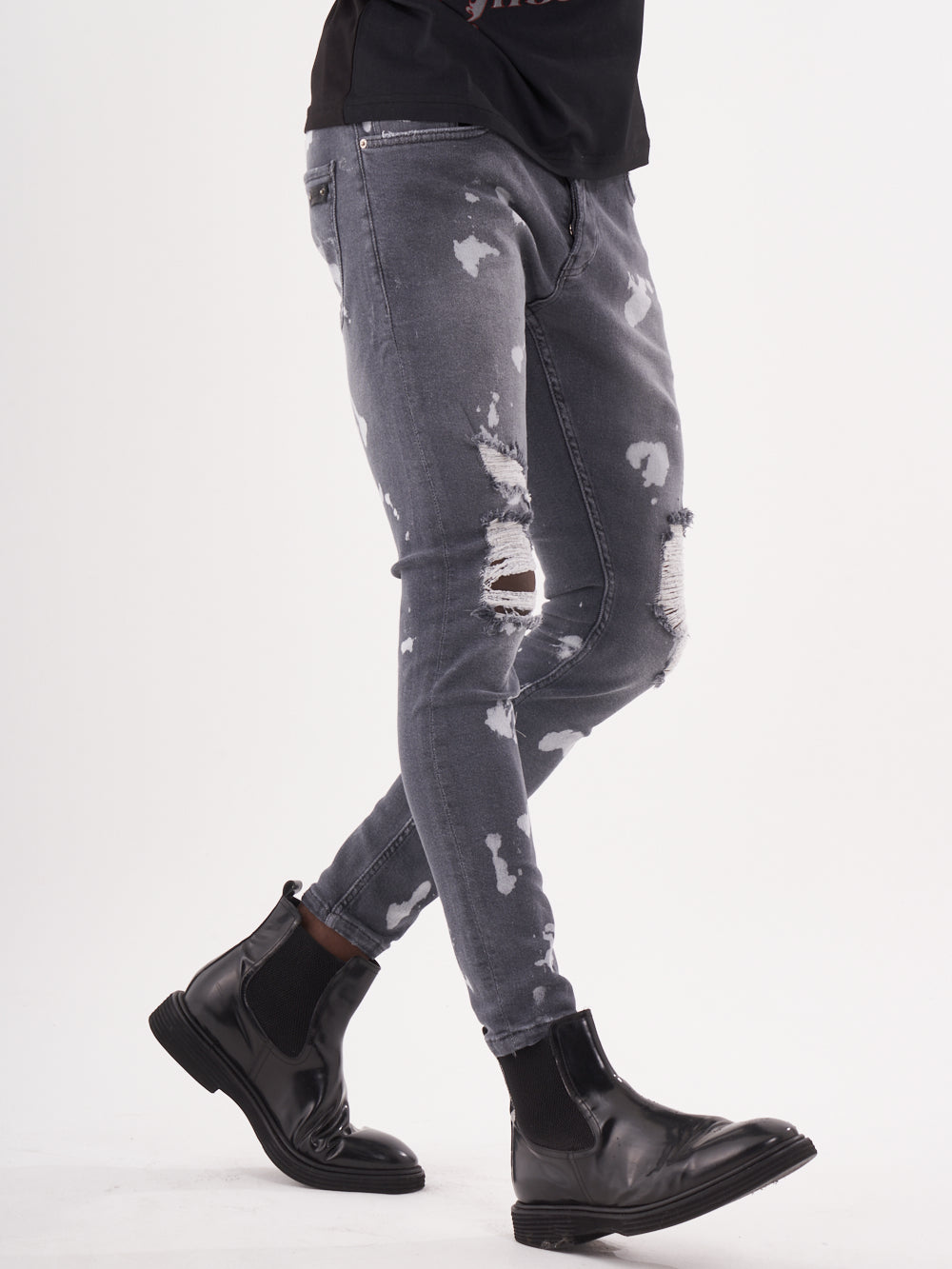 A man wearing grey ripped MAVERICK jeans and black MAVERICK boots.