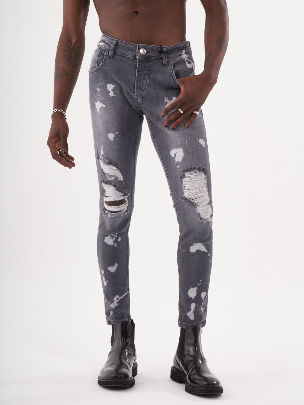 A man wearing ripped jeans and a MAVERICK t - shirt.