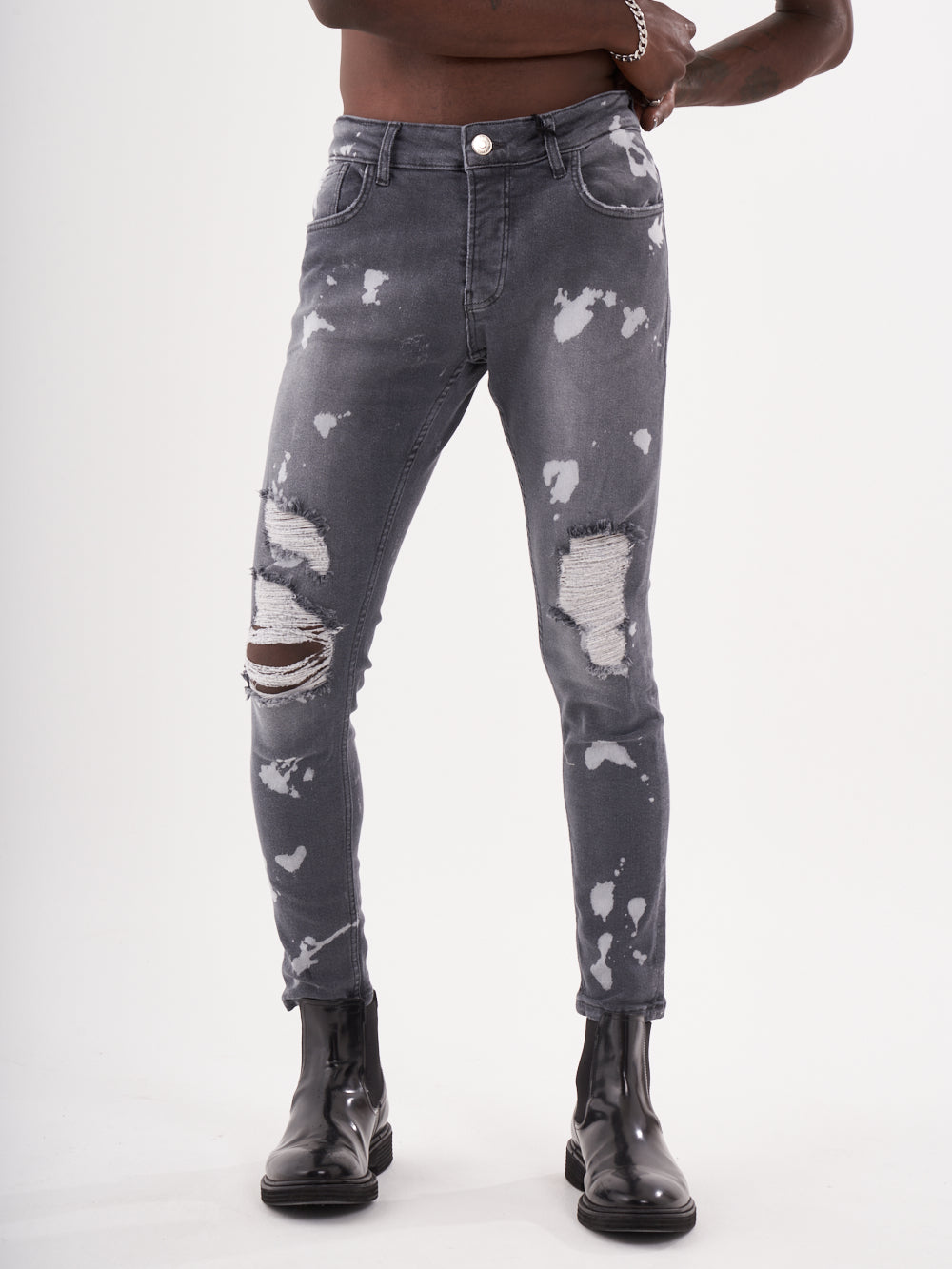 A man wearing grey ripped MAVERICK jeans and black boots.