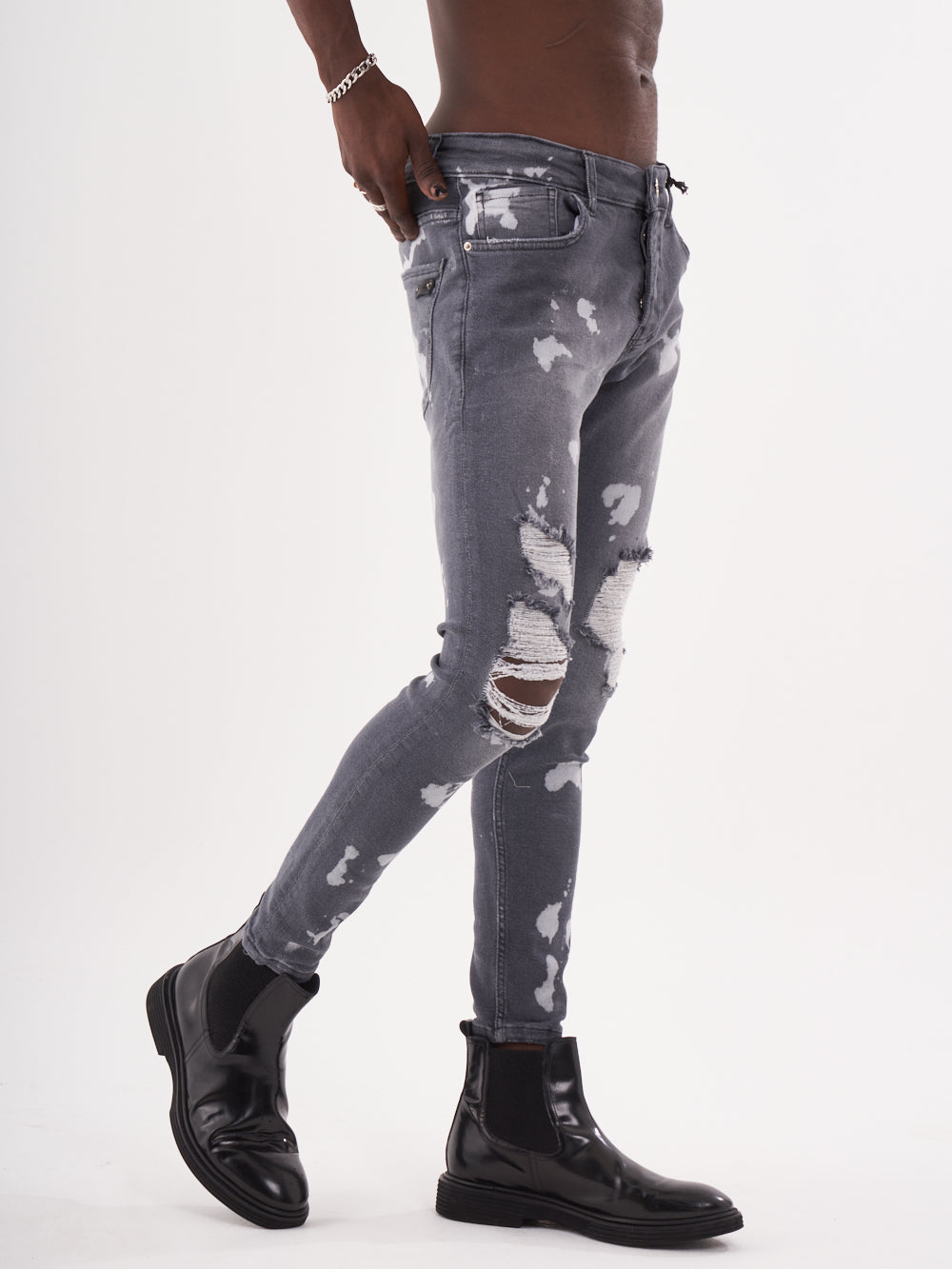 A man wearing ripped jeans and MAVERICK boots.