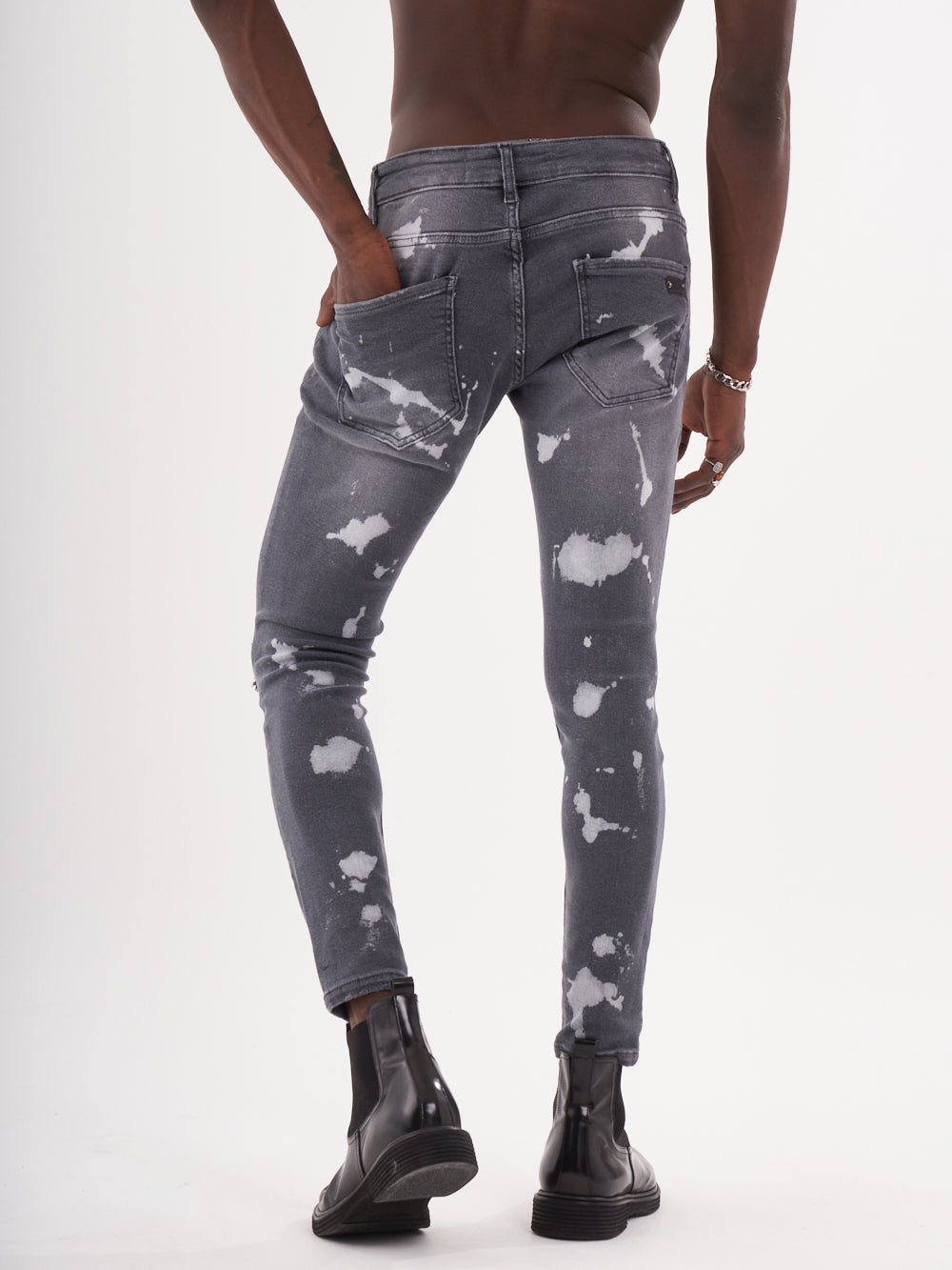 The back of a man in MAVERICK jeans with white paint splatters.