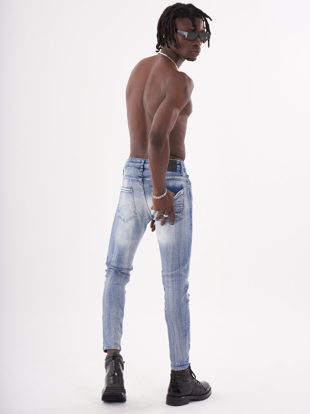 A man in blue jeans posing in front of a white background, holding the MUTANT.