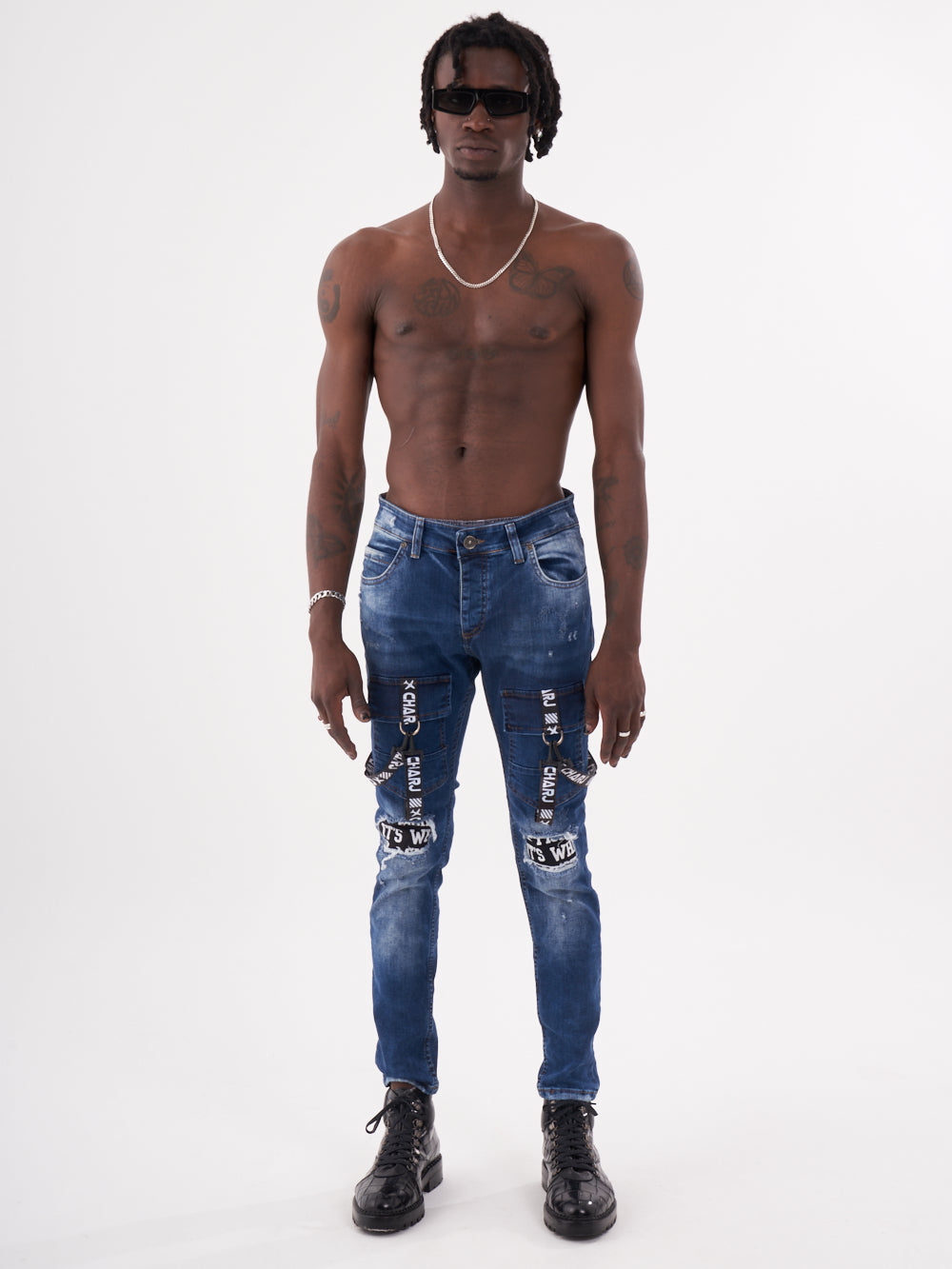 A man with no shirt and no shoes is standing in front of a TORNADO BLUE background.