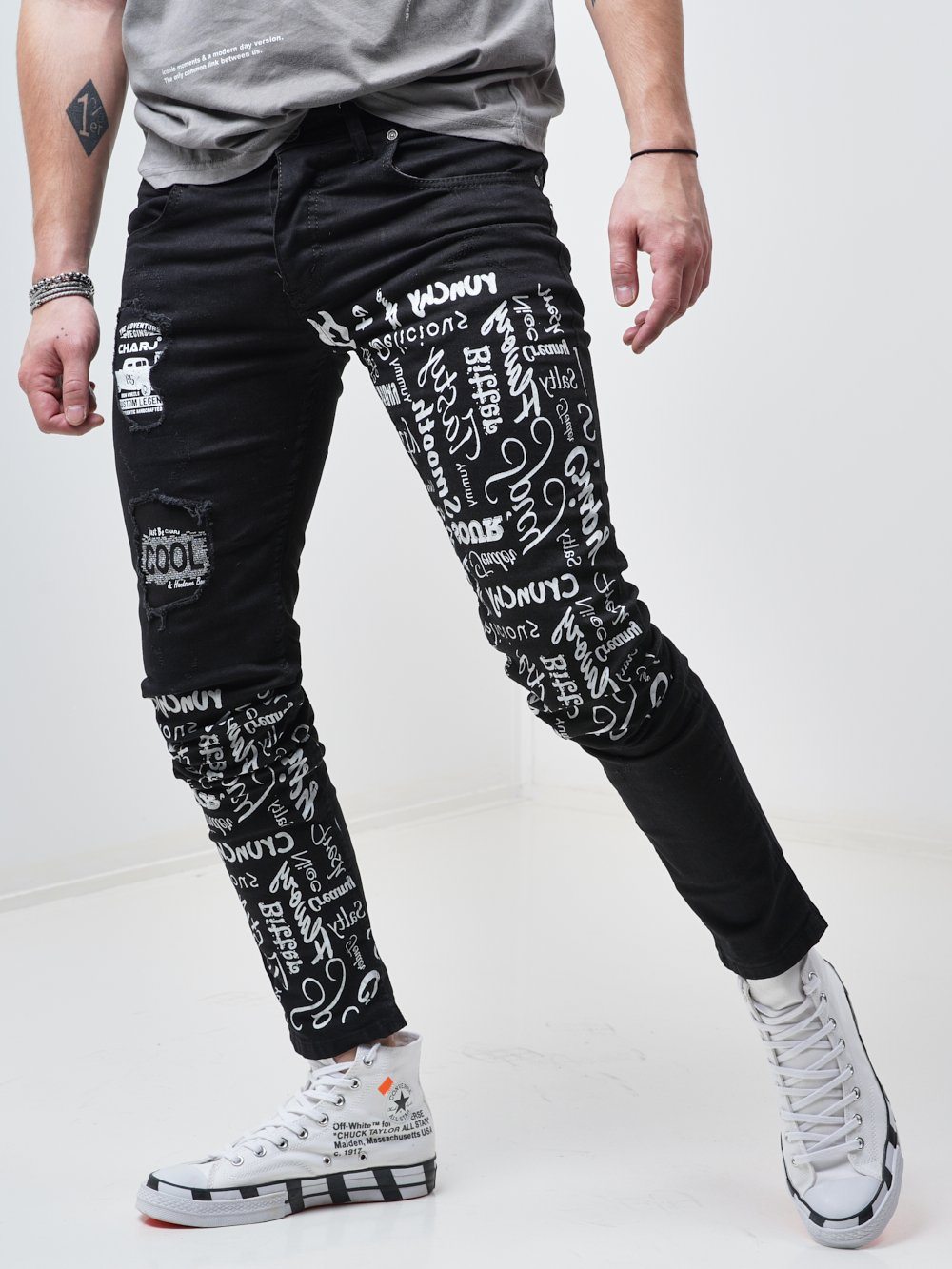 Side shot of a man wearing the skinny fit streetwear jeans called THE MECHANIC by SERNES with lots of text printed on it