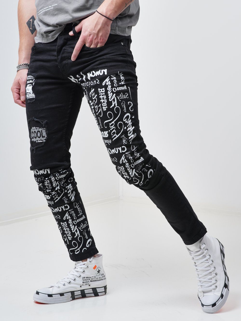 Side shot of a man sporting the skinny fit streetwear jeans called THE MECHANIC by SERNES with lots of text printed on it