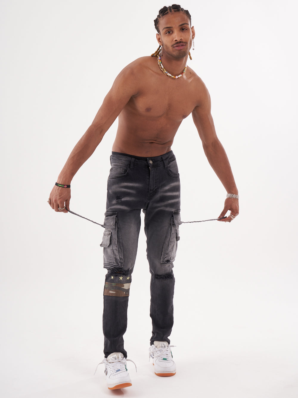 A HIPSTER with no shirt and jeans holding a rope.