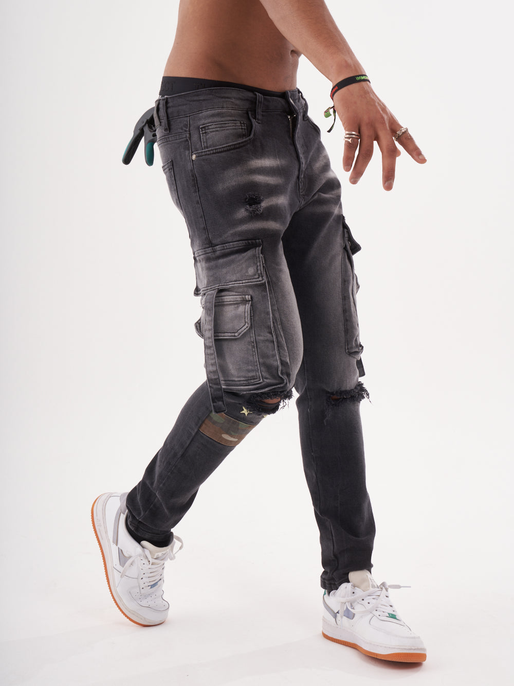 A man in ripped jeans and sneakers is standing in front of a white background wearing the HIPSTER.