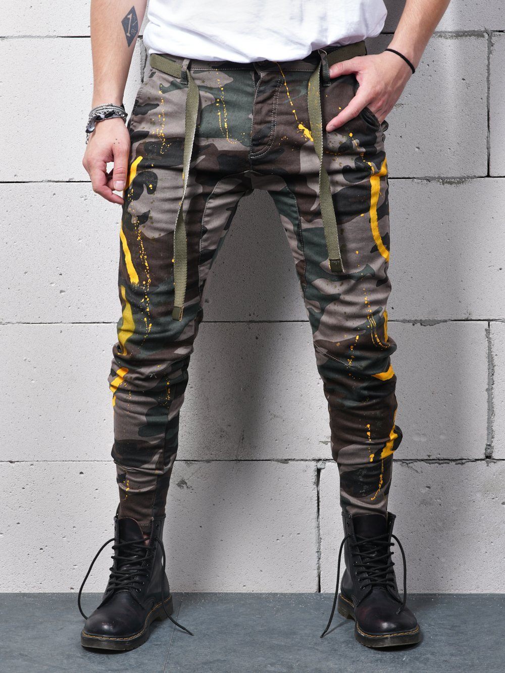 A man wearing KONGOS skinny fit camouflage pants with yellow stripes.