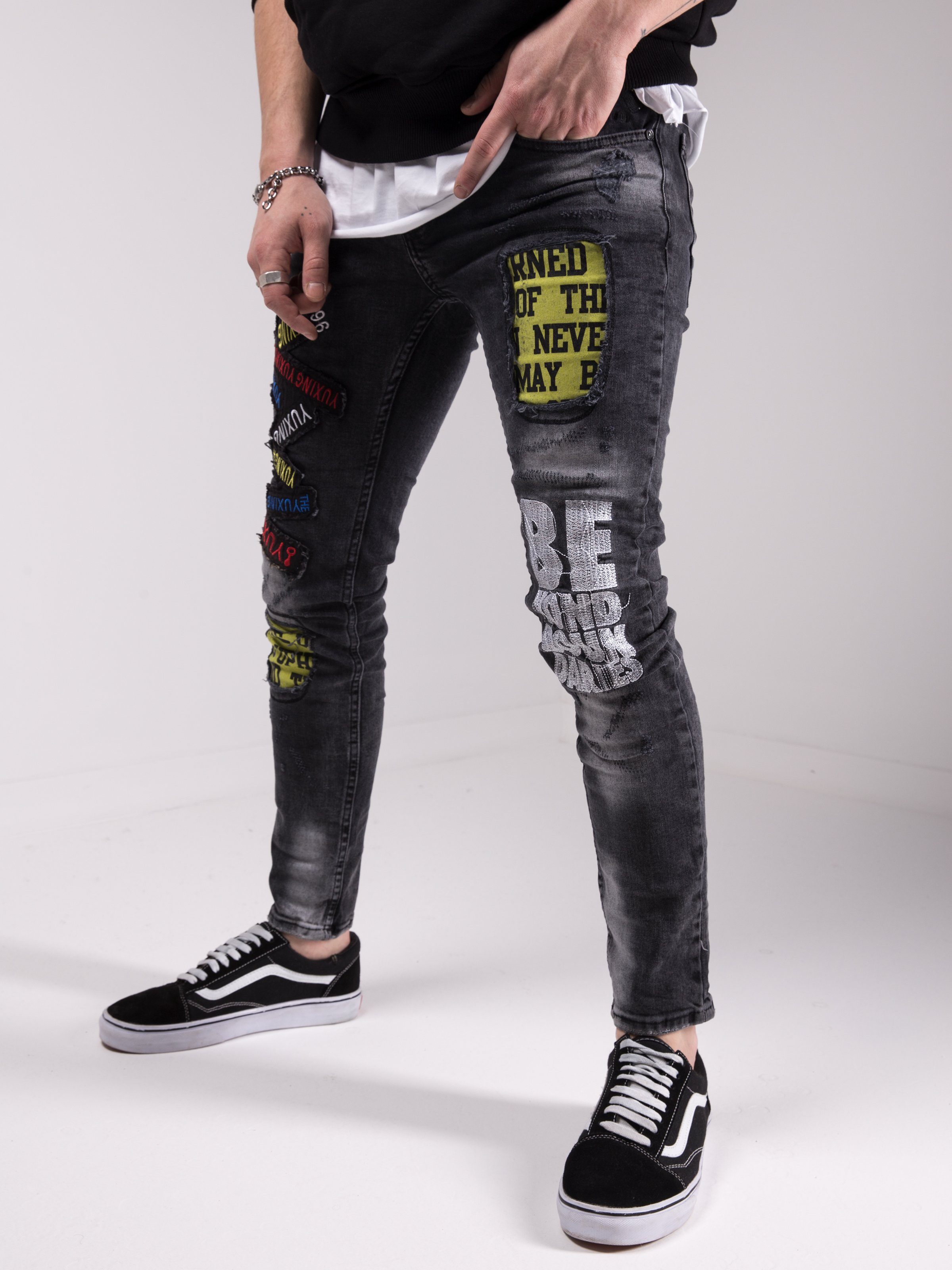 A man wearing a pair of Savage Secret jeans with patches on them.