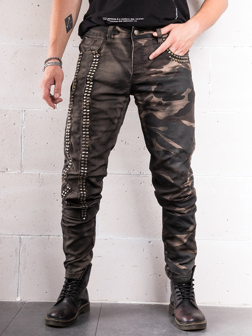 A man wearing a black t-shirt and camouflage pants with Sniper handcrafted details.