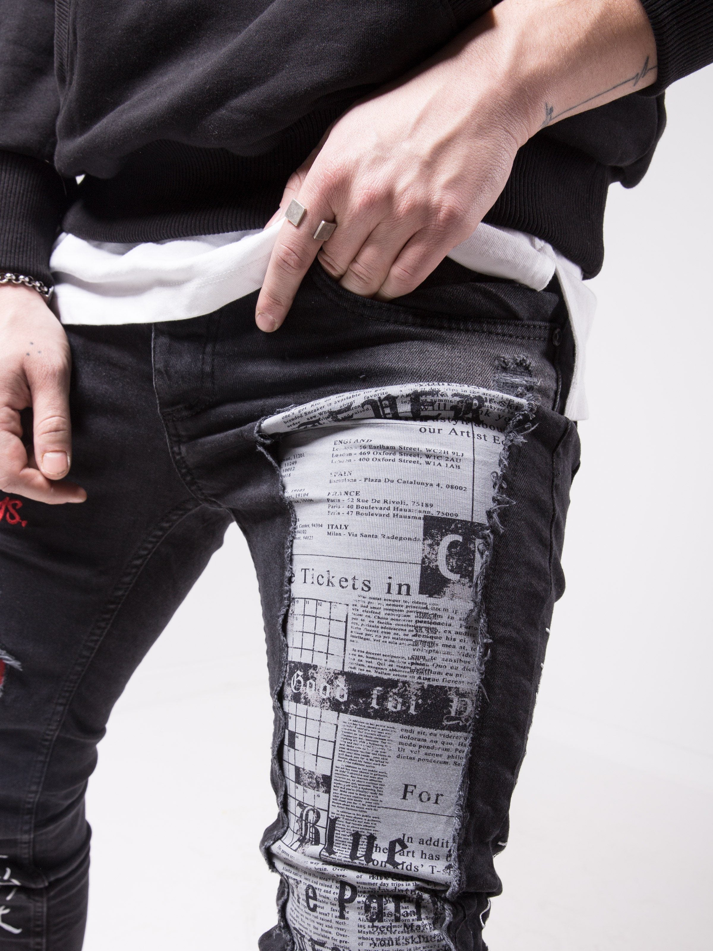 A man is wearing a pair of black SKYSCRAPER jeans with a black hoodie.
