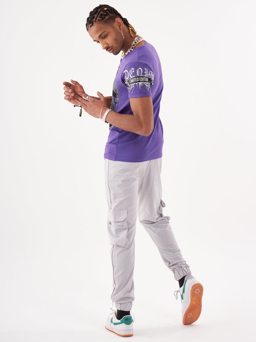 A man wearing a SKULL CRUSHER T-SHIRT | PURPLE and gray pants.