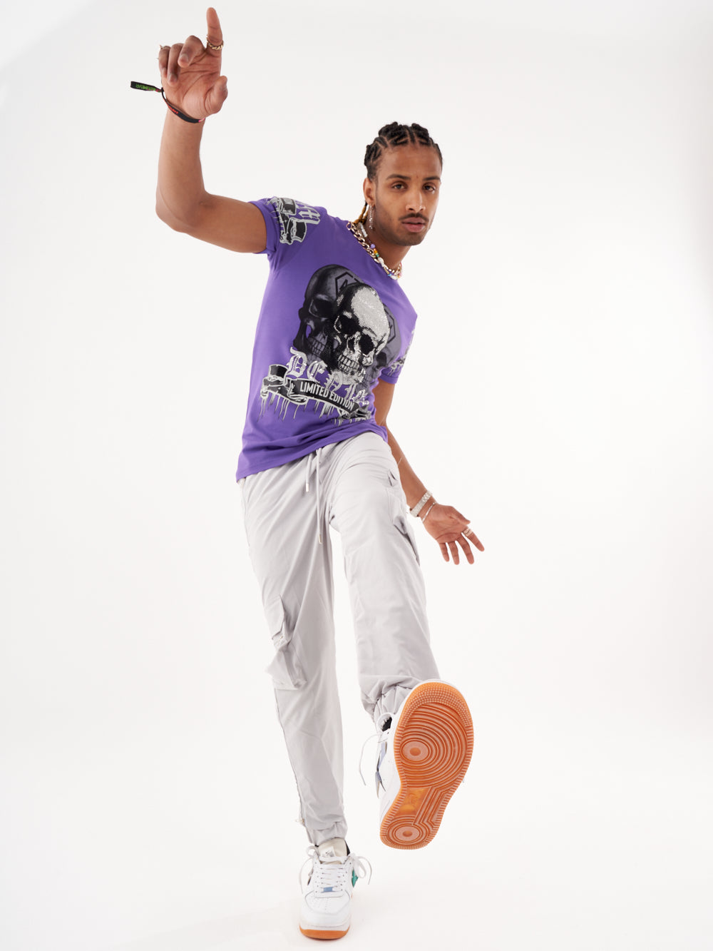 A man in a SKULL CRUSHER T-SHIRT | PURPLE is posing in front of a white background.