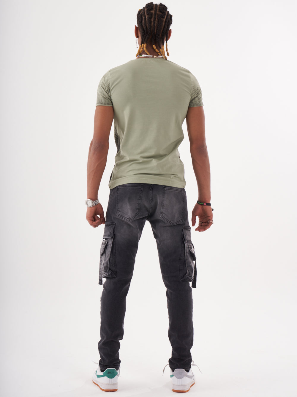 The back view of a man wearing a NIRVANA T-SHIRT | GREEN and cargo pants.
