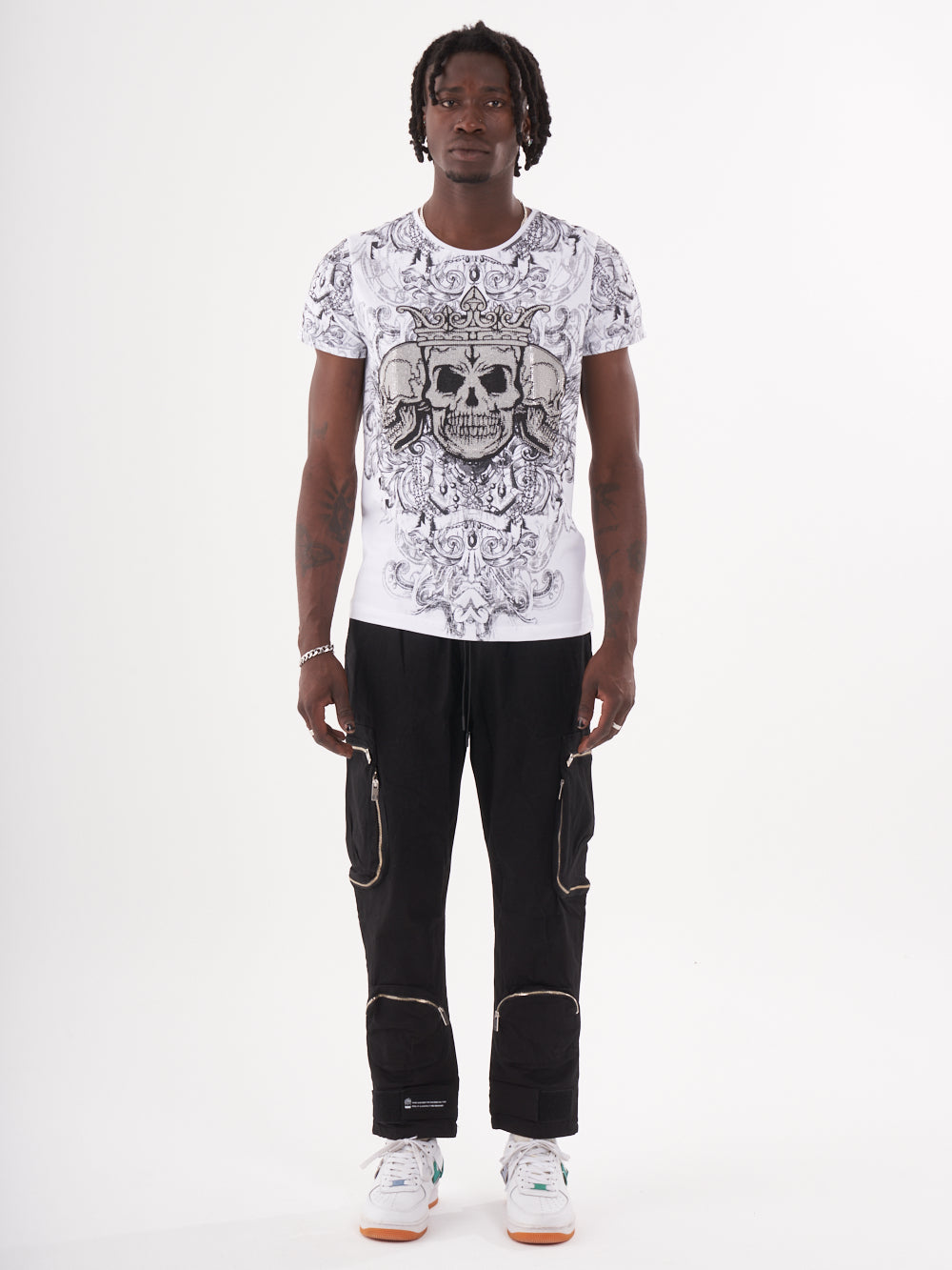 The man is wearing a TRINITY T-SHIRT | WHITE with skulls on it.