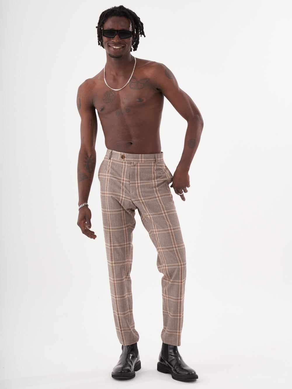A man with no shirt and ROOK PANTS is posing for a photo.