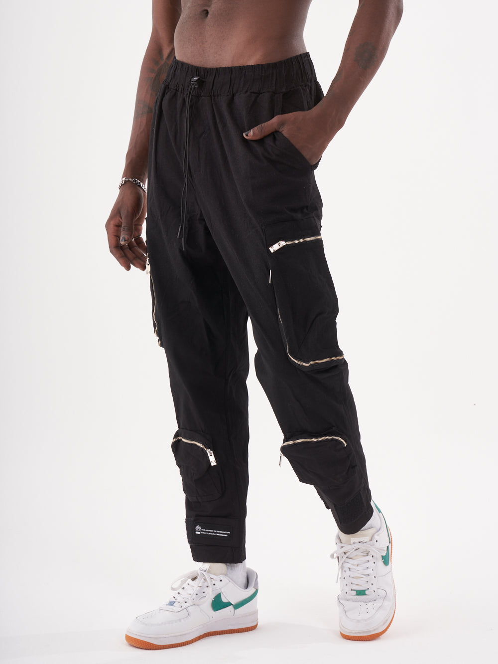 A man wearing black Raider joggers and white sneakers.