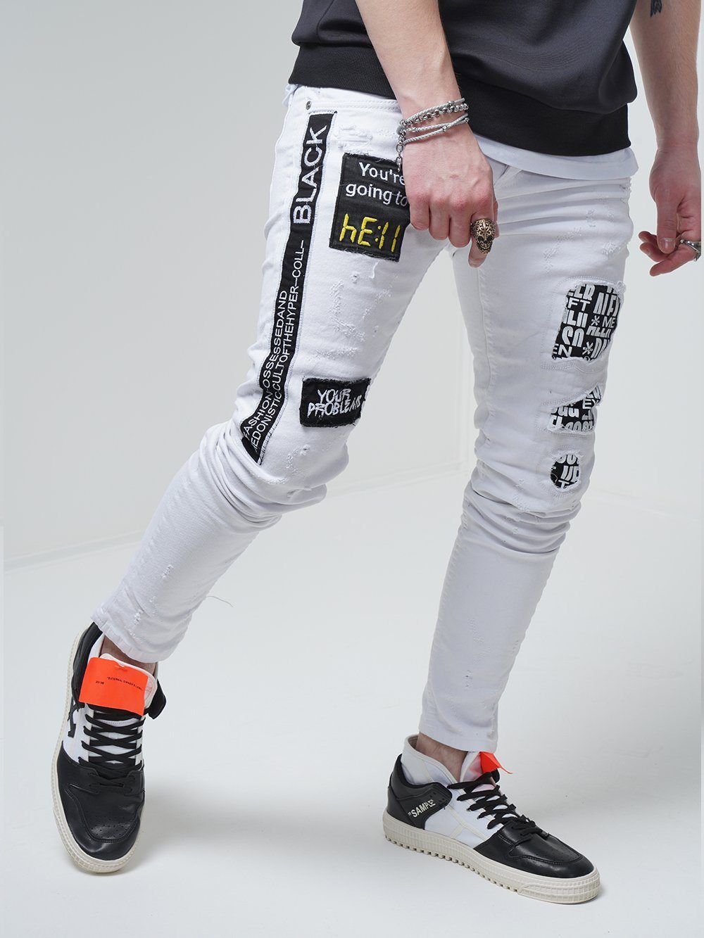 A man wearing the WHITE FALCON jeans with patches on them.