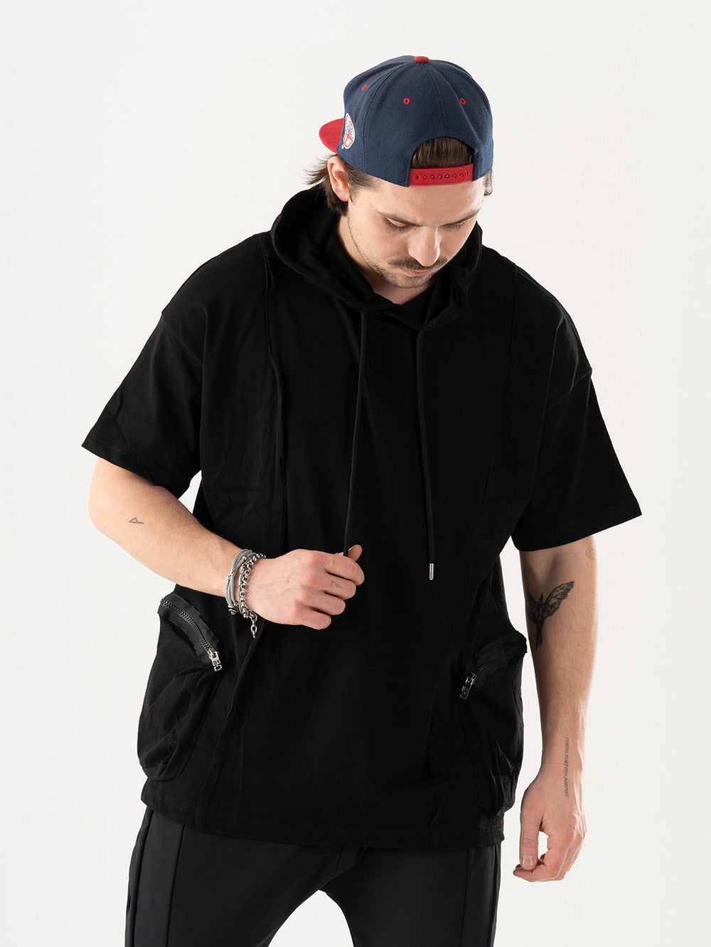 A stylish man wearing the BLACKFURY HOODIE, a black color staple with convenient pockets.