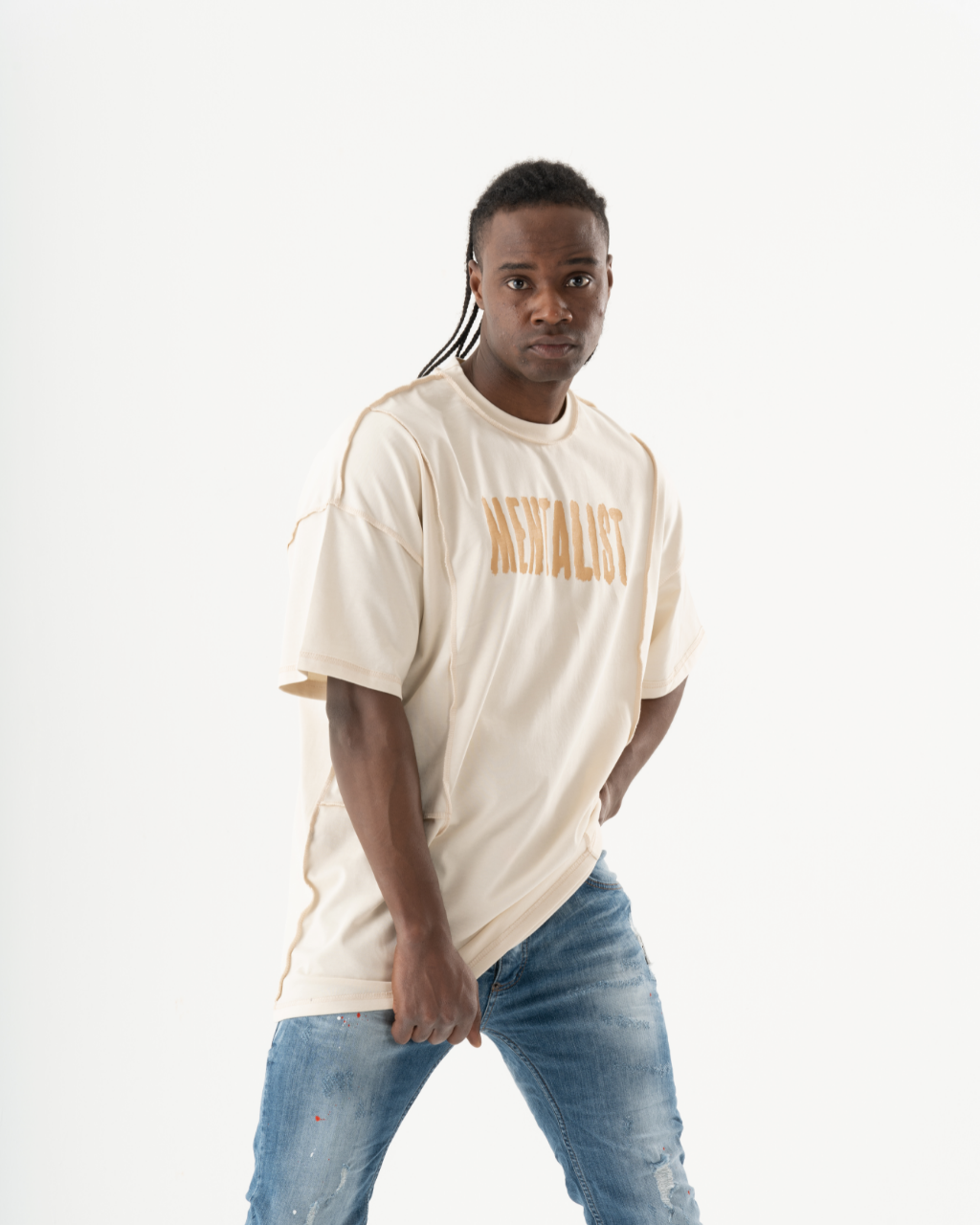 A man in a MENTALIST T-SHIRT | BEIGE and jeans posing for a photo.