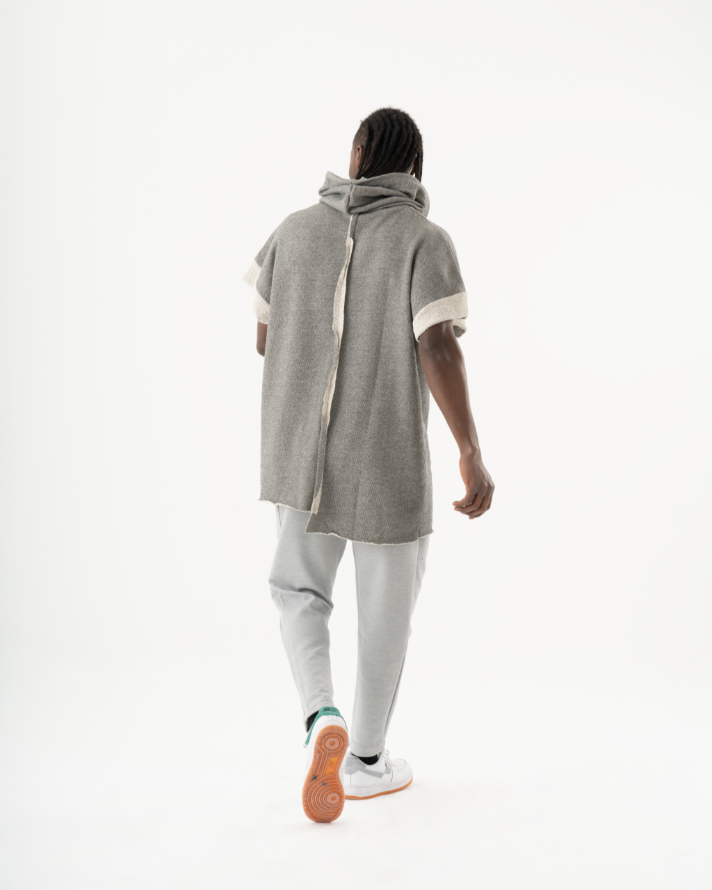 A man wearing a HAILMARY HOODIE grey hoodie and sneakers walking down a white background with a comfortable fit.