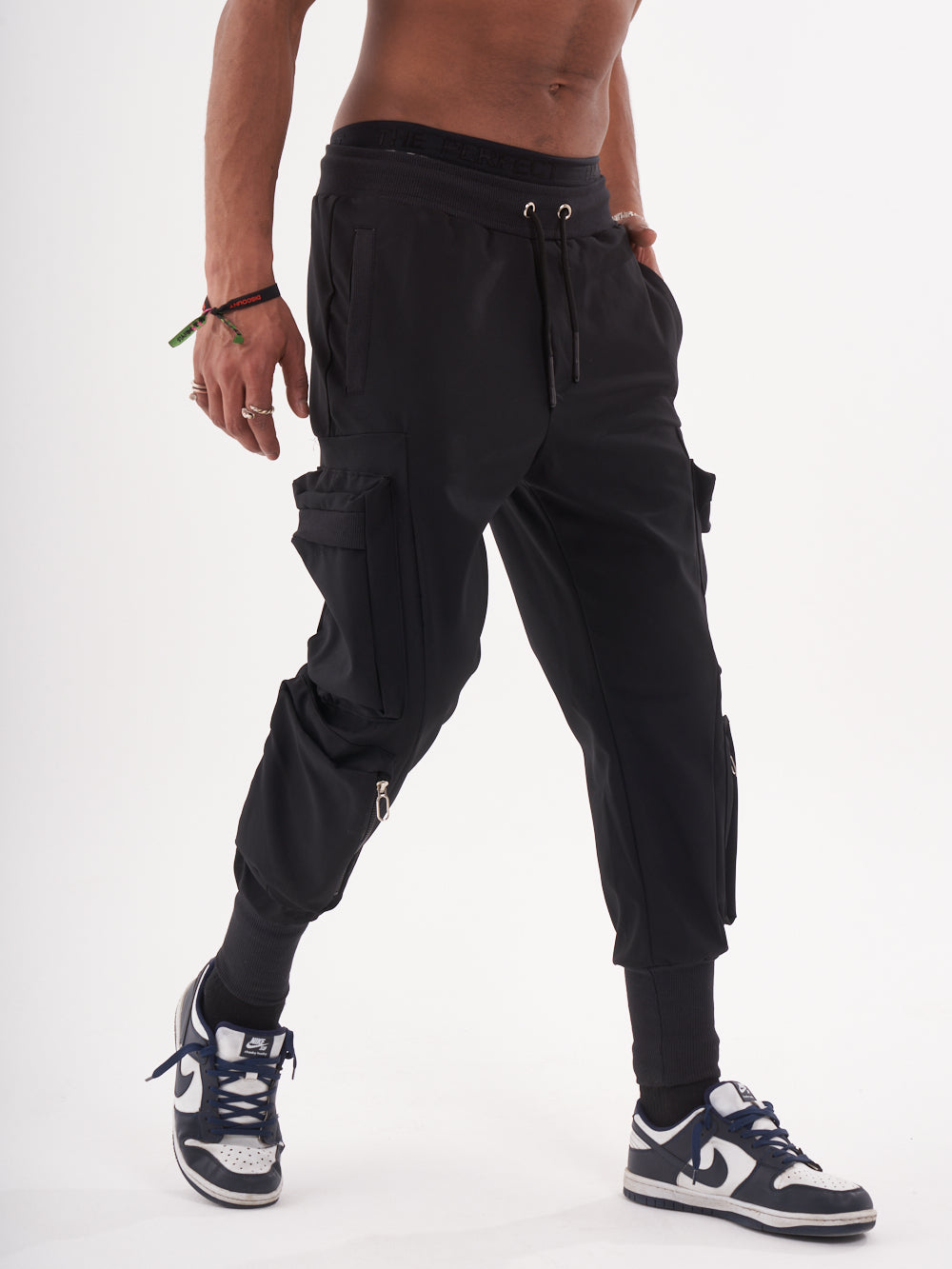 A man in OUTLIER JOGGERS | BLACK is standing on a white background.