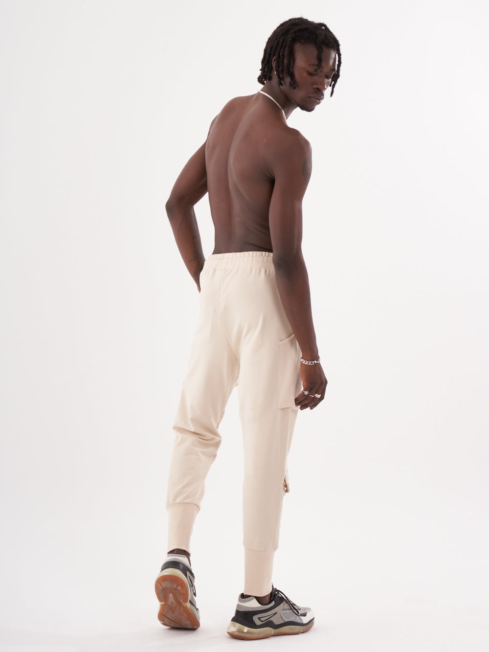 The back view of a man in GUERRILLA | BEIGE sweatpants.