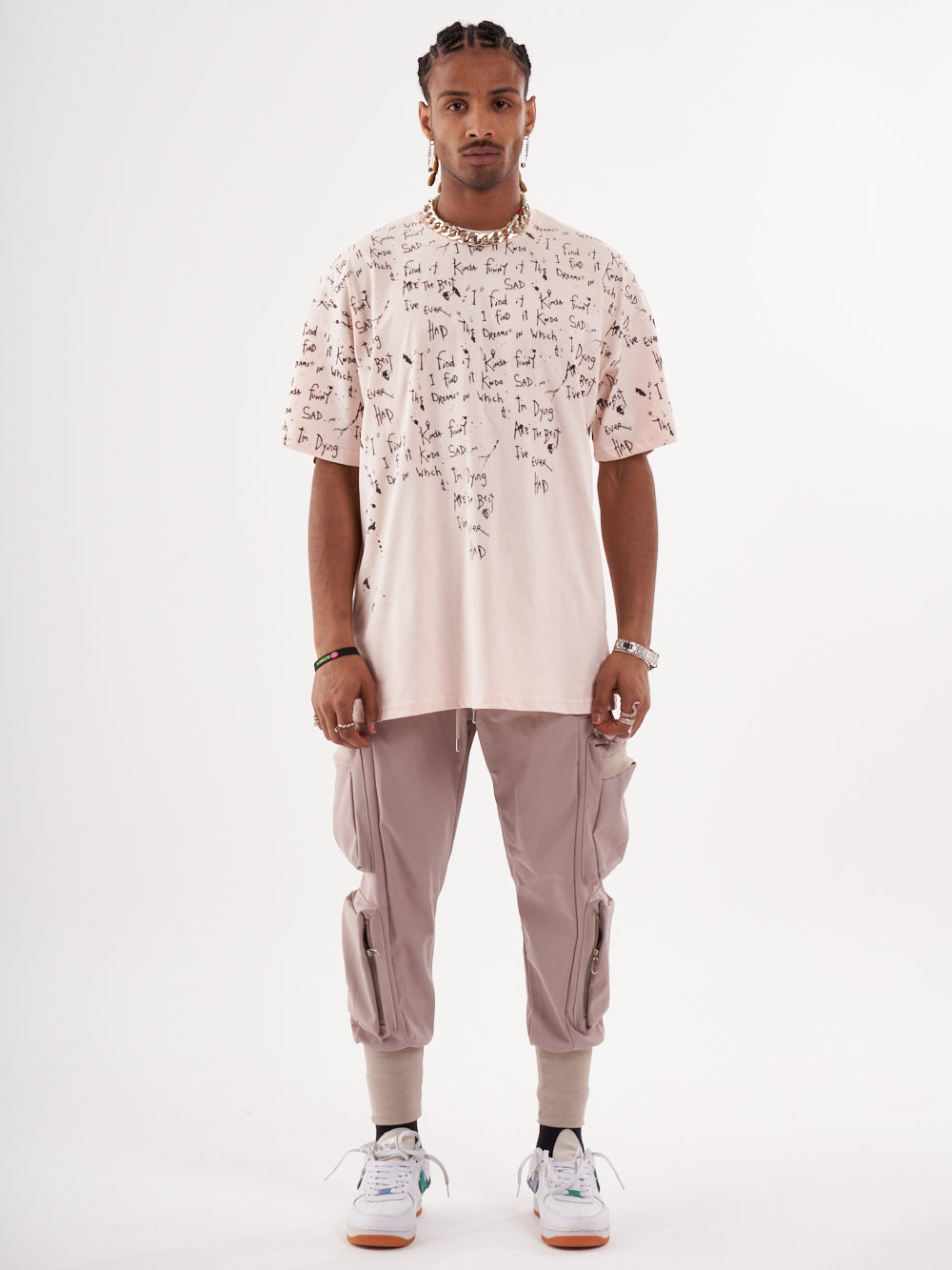 The man is wearing a pink THINKER T-SHIRT with writing on it.