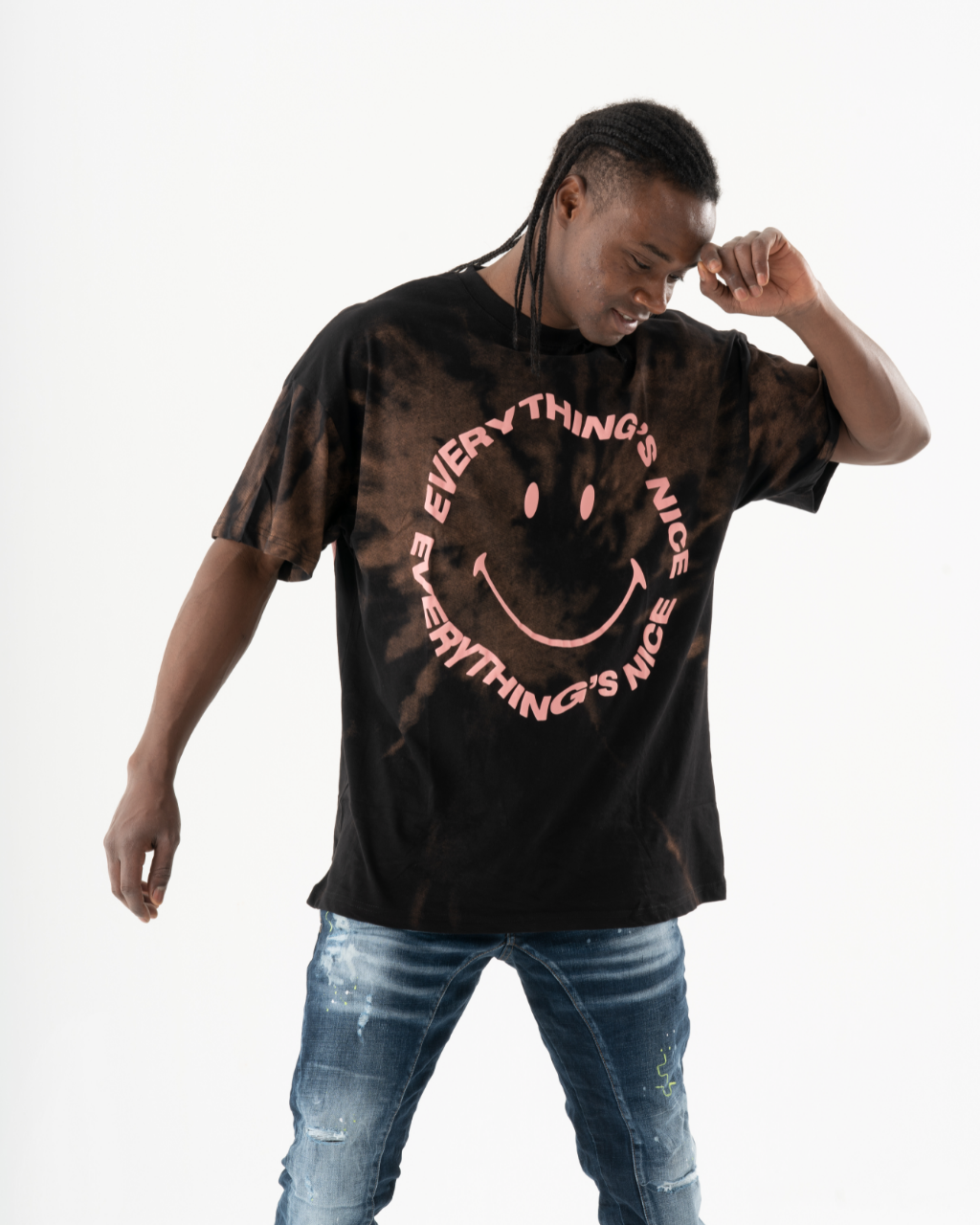 A man wearing an oversize Optimist T-shirt with a smiley face on it.