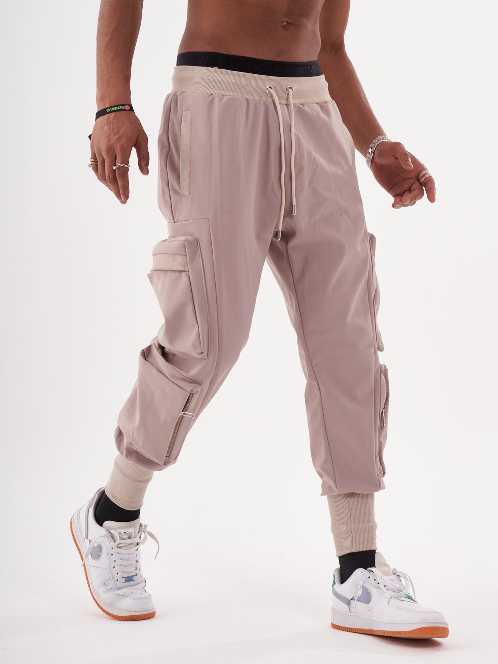 A man wearing OUTLIER | MAUVE cargo pants and white sneakers.