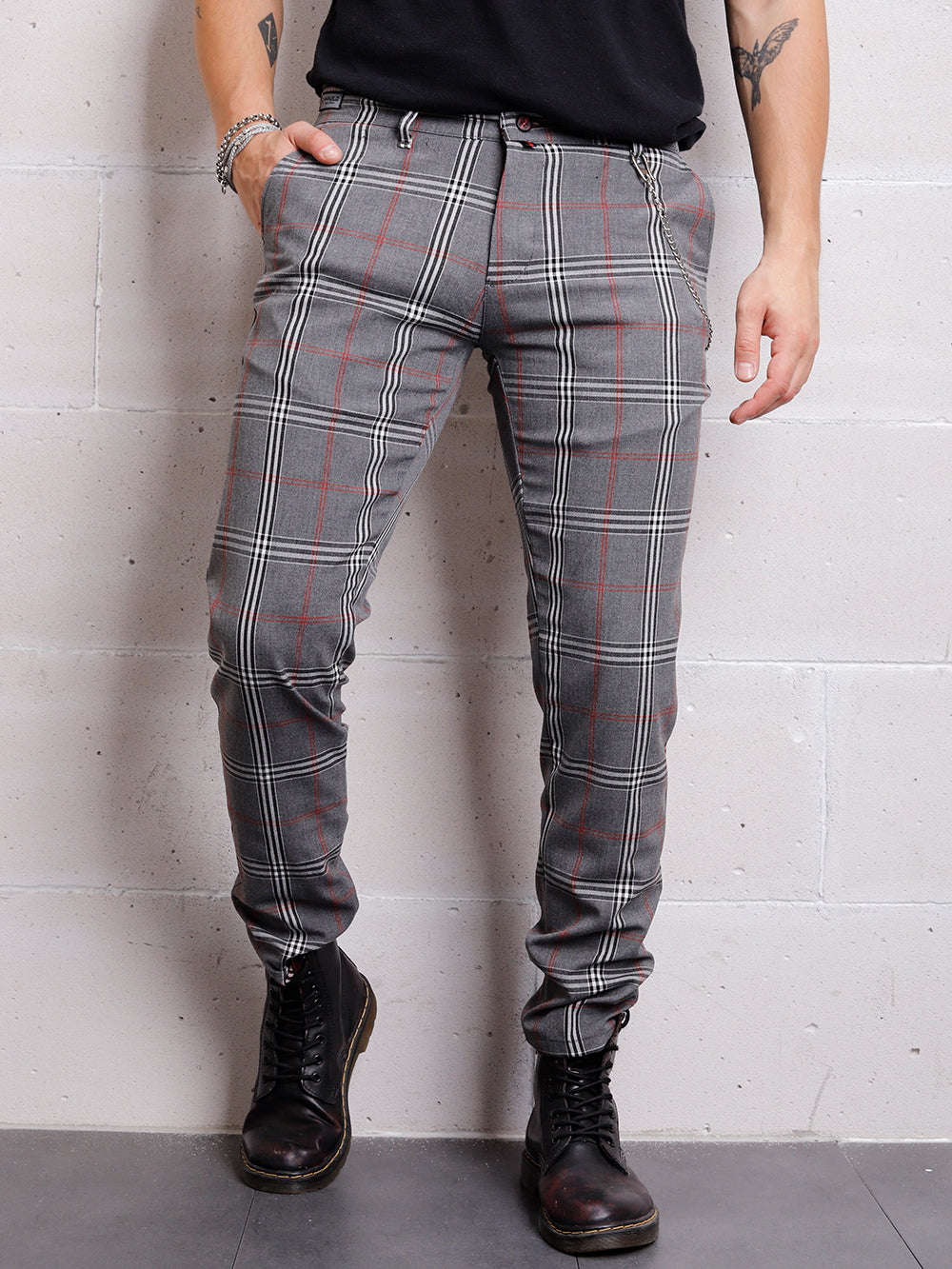 A man wearing a CHECKERED GREY jogging pant standing against a wall.