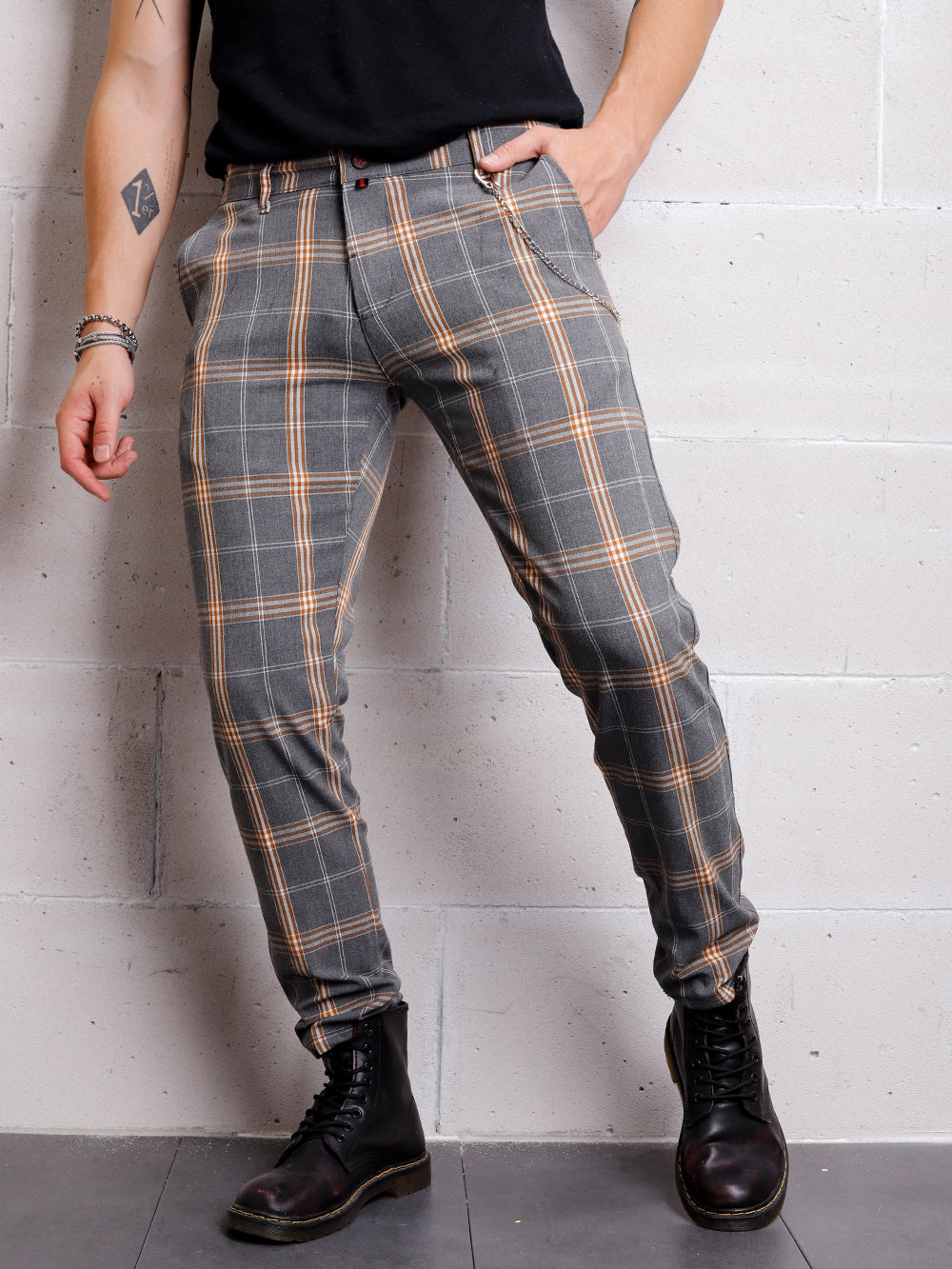 A man in slim-fit, CHECKERED STONE trouser pants leaning against a wall.