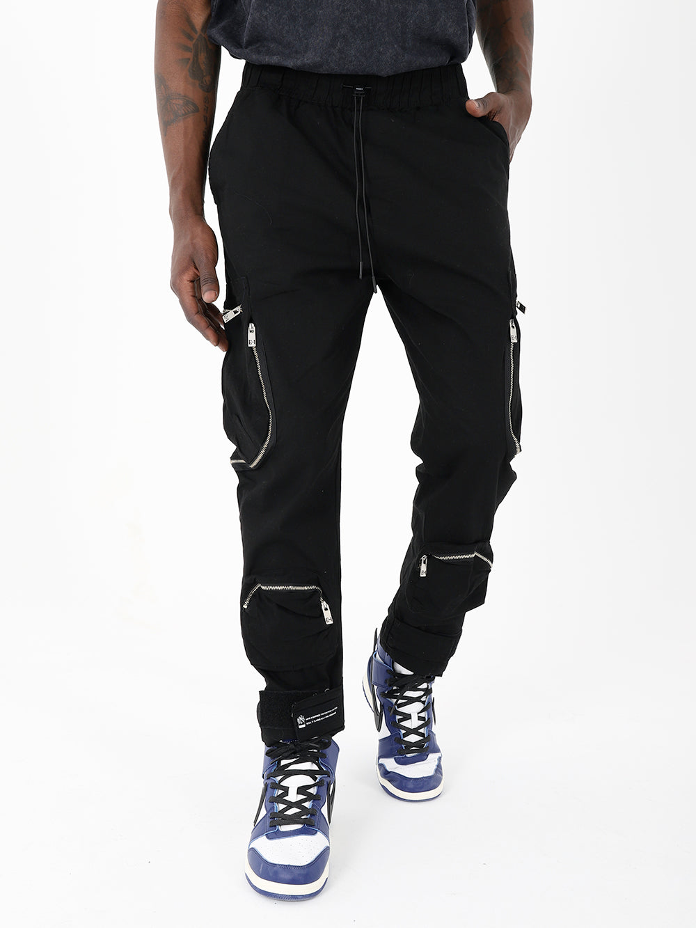 A man wearing Raider Joggers, black cargo pants with zippers.