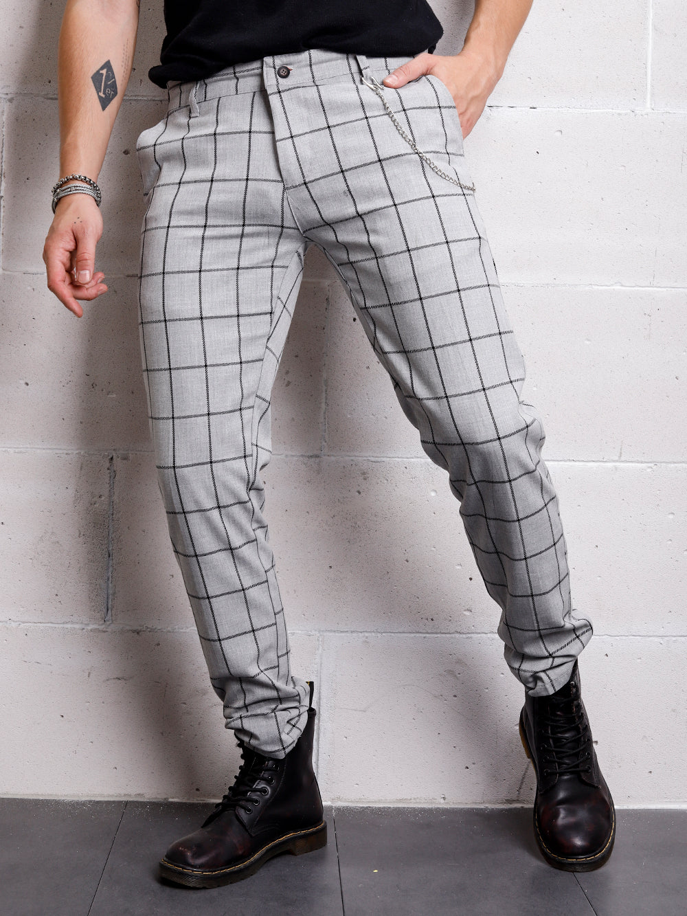 A gentleman in GRAYSTONE PANTS is leaning against a wall.