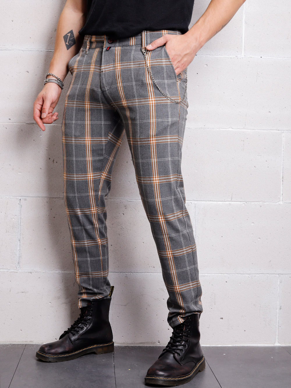 A man in slim fit CHECKERED STONE trouser pants standing against a wall.