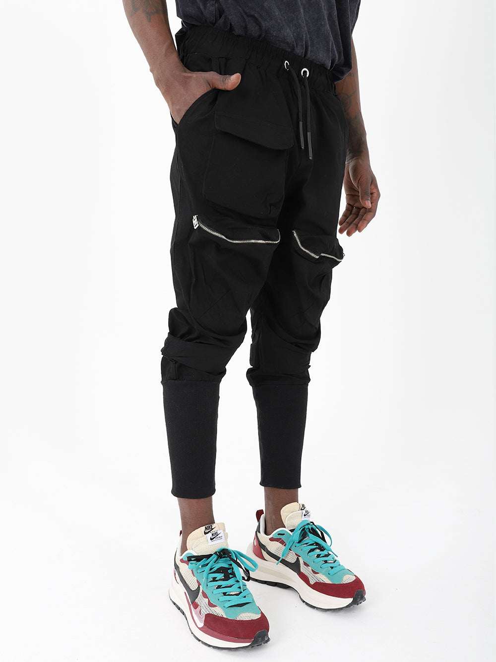 A man wearing MEREEN jogger pants and sneakers.