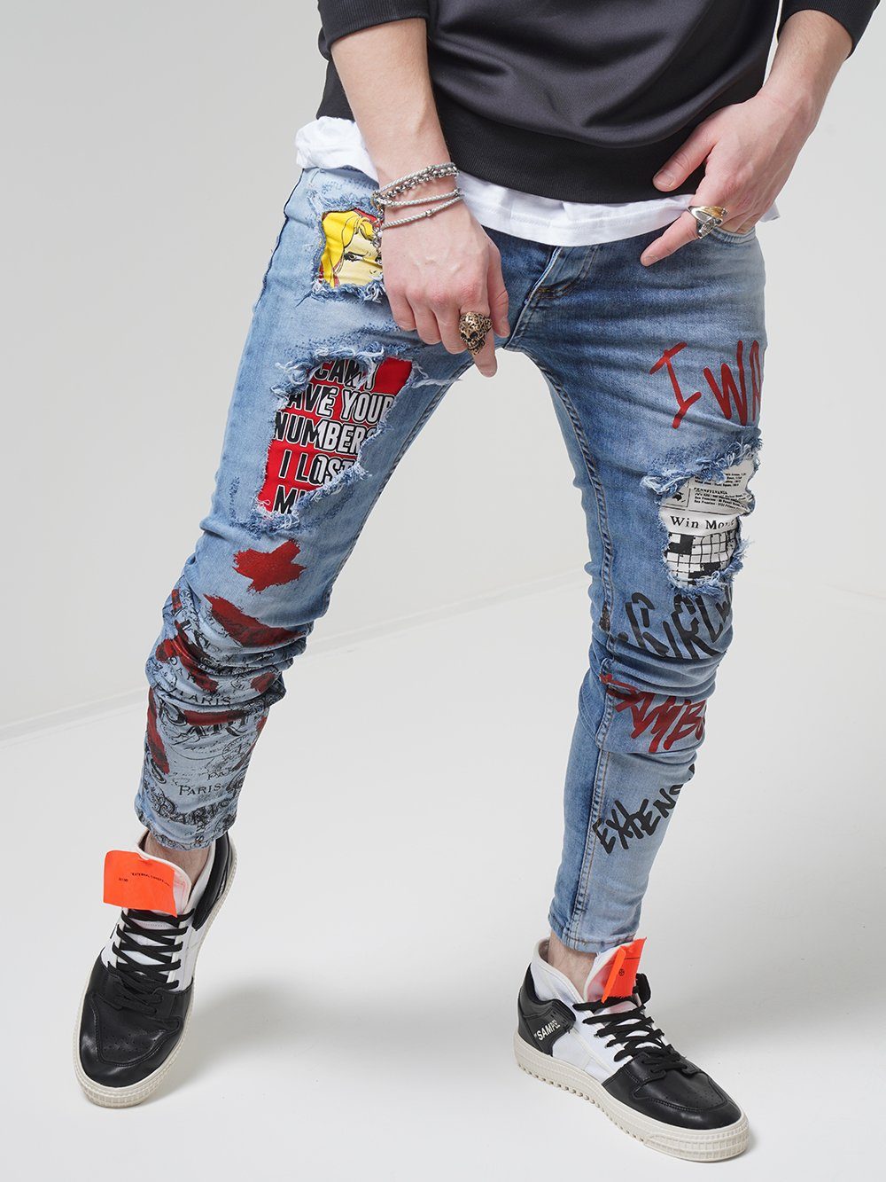 A man wearing a pair of BANKSY jeans with graffiti on them.