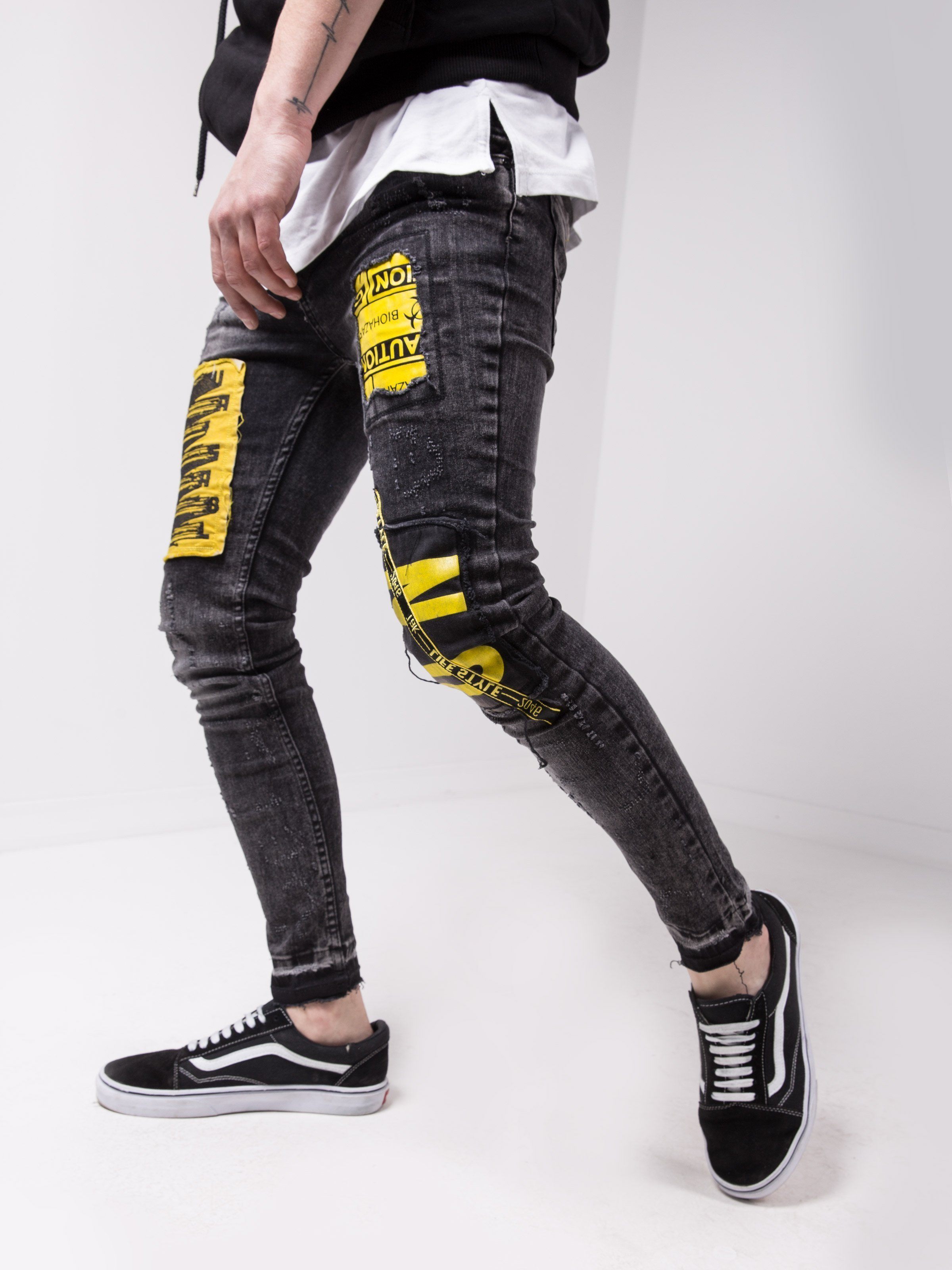 A man wearing a pair of MOUNT ONE jeans with yellow tape on them.