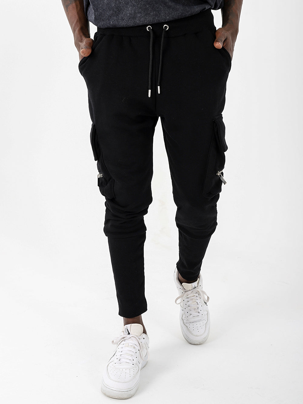 A man wearing comfortable black RAMBO joggers with pockets and a white t-shirt.