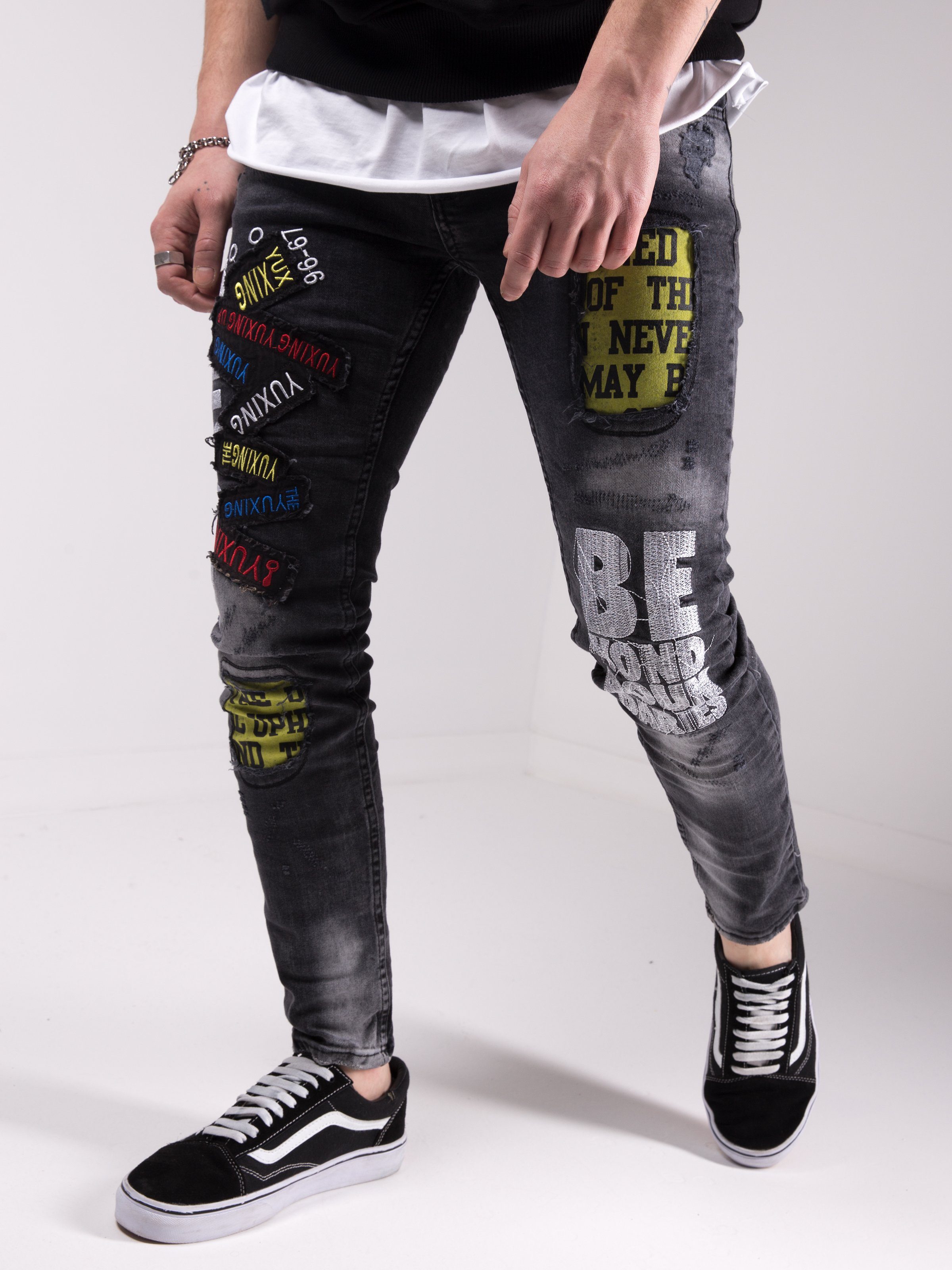 A man wearing a pair of SAVAGE SECRET jeans with patches on them.