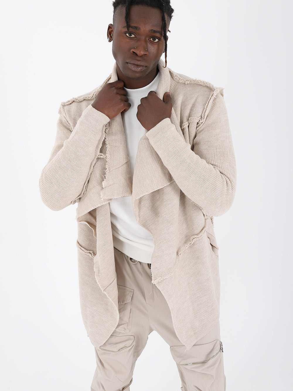 A man is posing in an ivory ASYMMETRIC SHORT CARDIGAN.