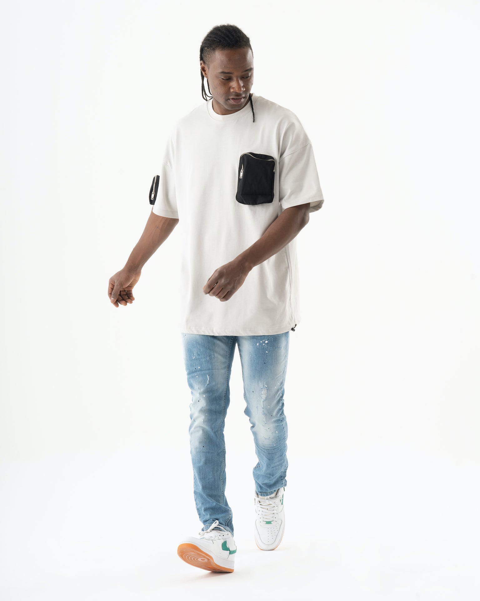 A man in a white t - shirt and jeans walking, wearing skinny fit SKATER jeans.