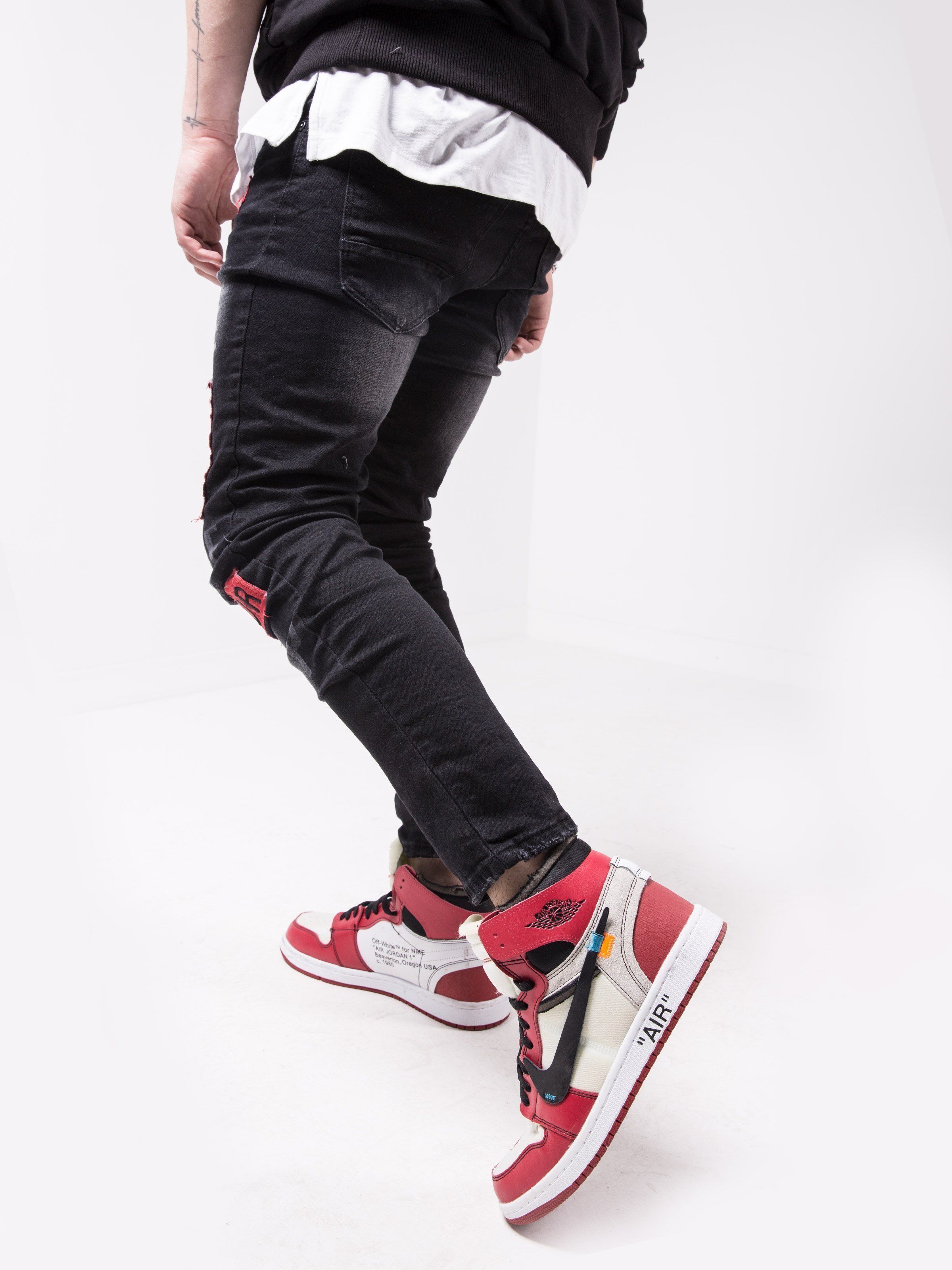 A man in black and red GHETTO BIRD is standing in front of a white background.