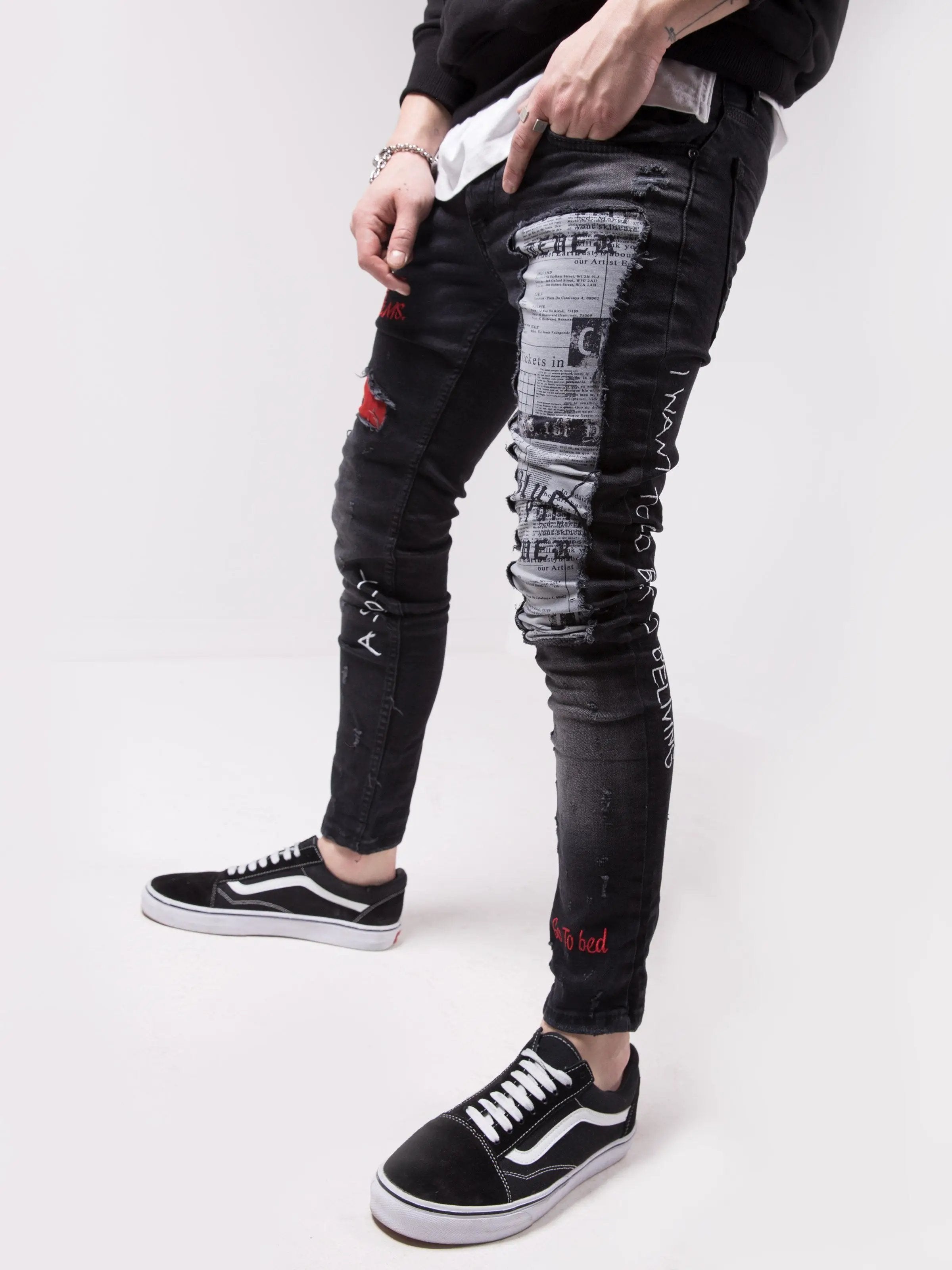 A man wearing SKYSCRAPER ripped jeans and a white t-shirt.