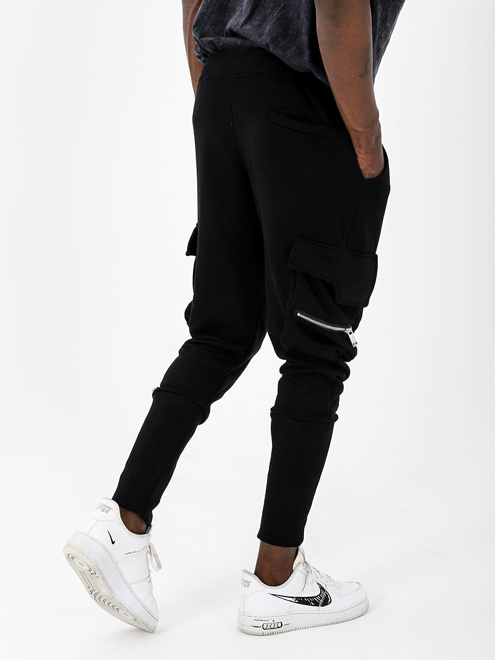 A man wearing comfortable black RAMBO joggers with pockets, paired with stylish white sneakers.