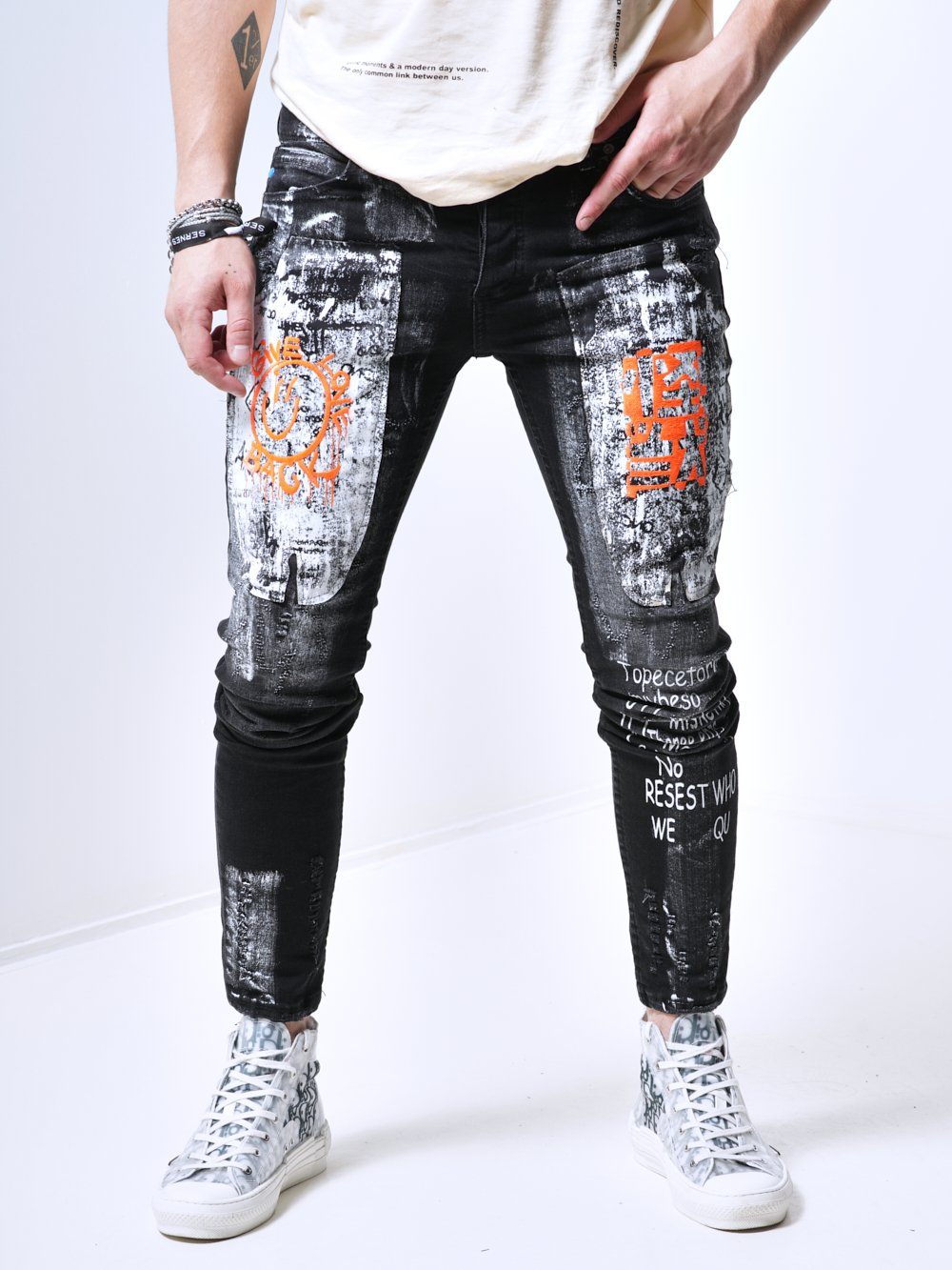 A man wearing a pair of SIXTY SIX black jeans with an orange t-shirt.